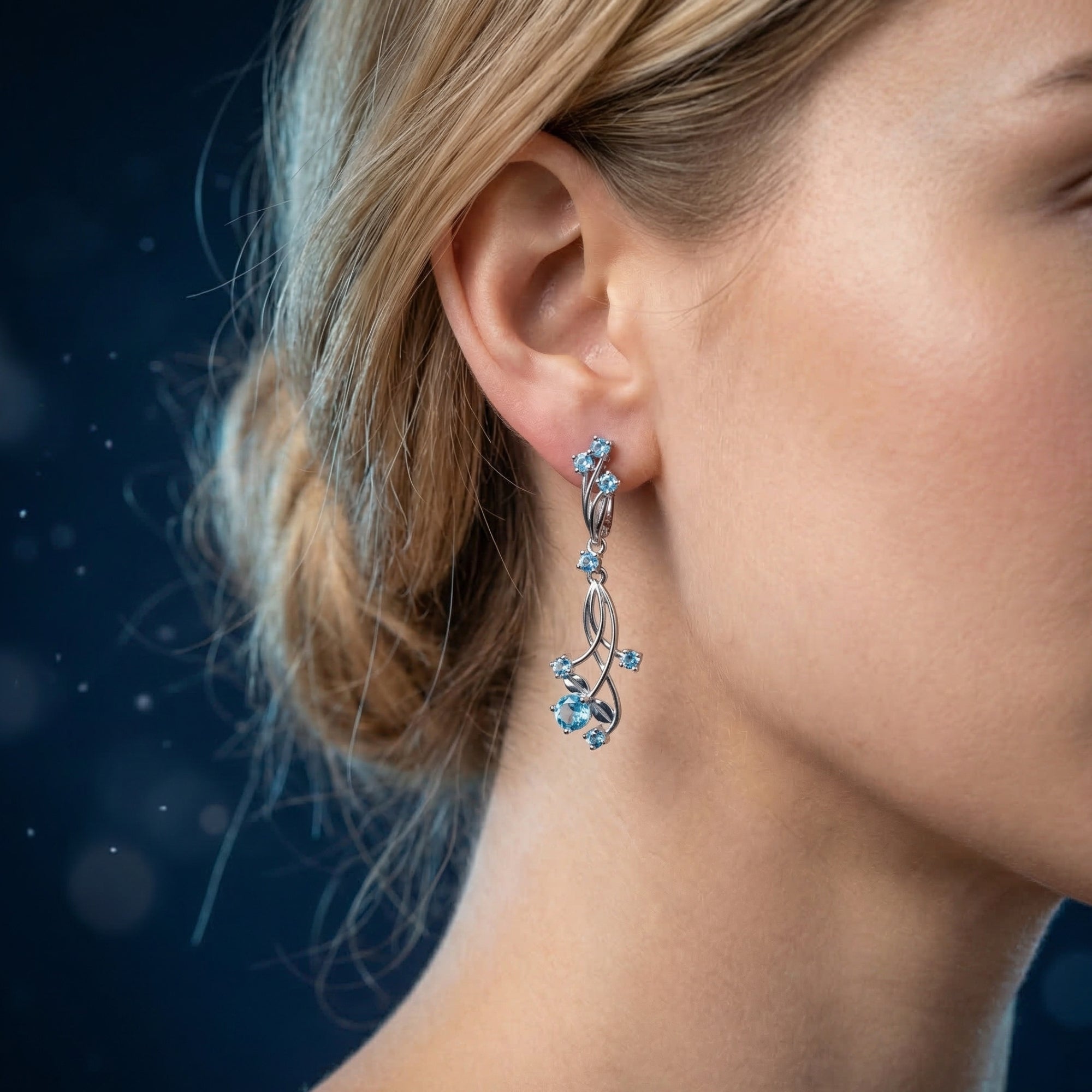 Blonde model wearing the Oceanis Cascade silver drop earrings featuring pear-cut natural blue topaz gemstones.