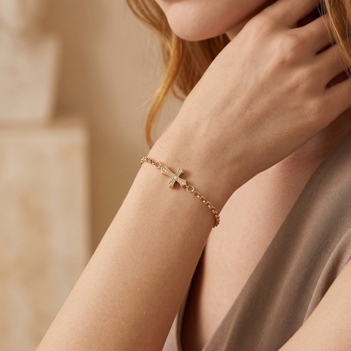 Lifestyle view of a person wearing a gold-tone cross bracelet with sparkling stones on the wrist.