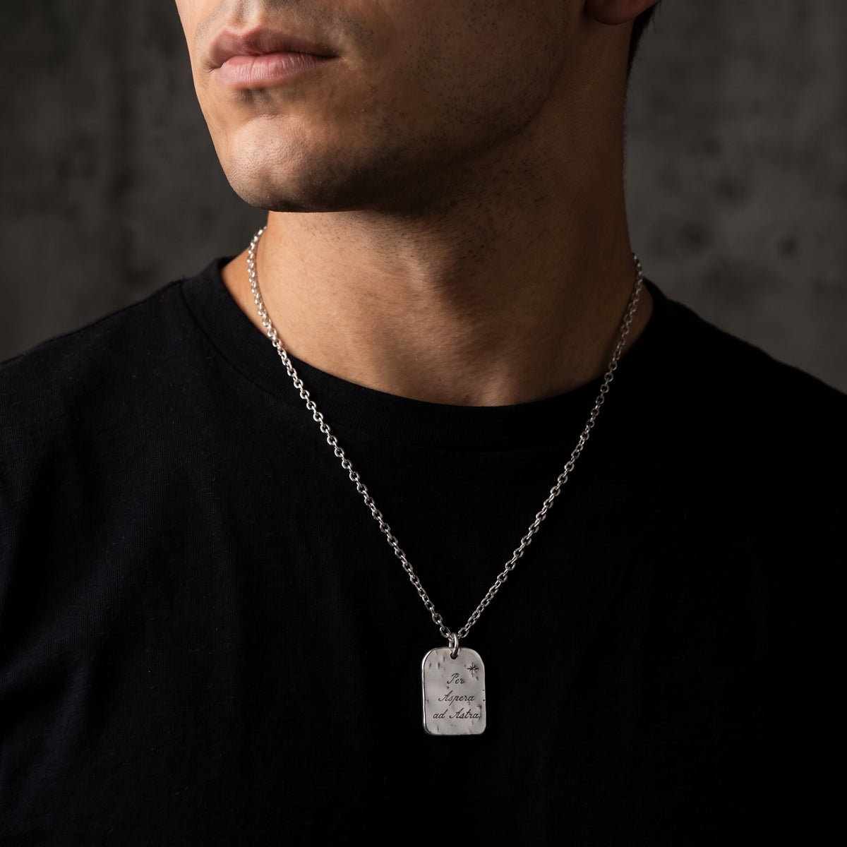 Cropped view of a man wearing the silver star tag pendant necklace over a black shirt.