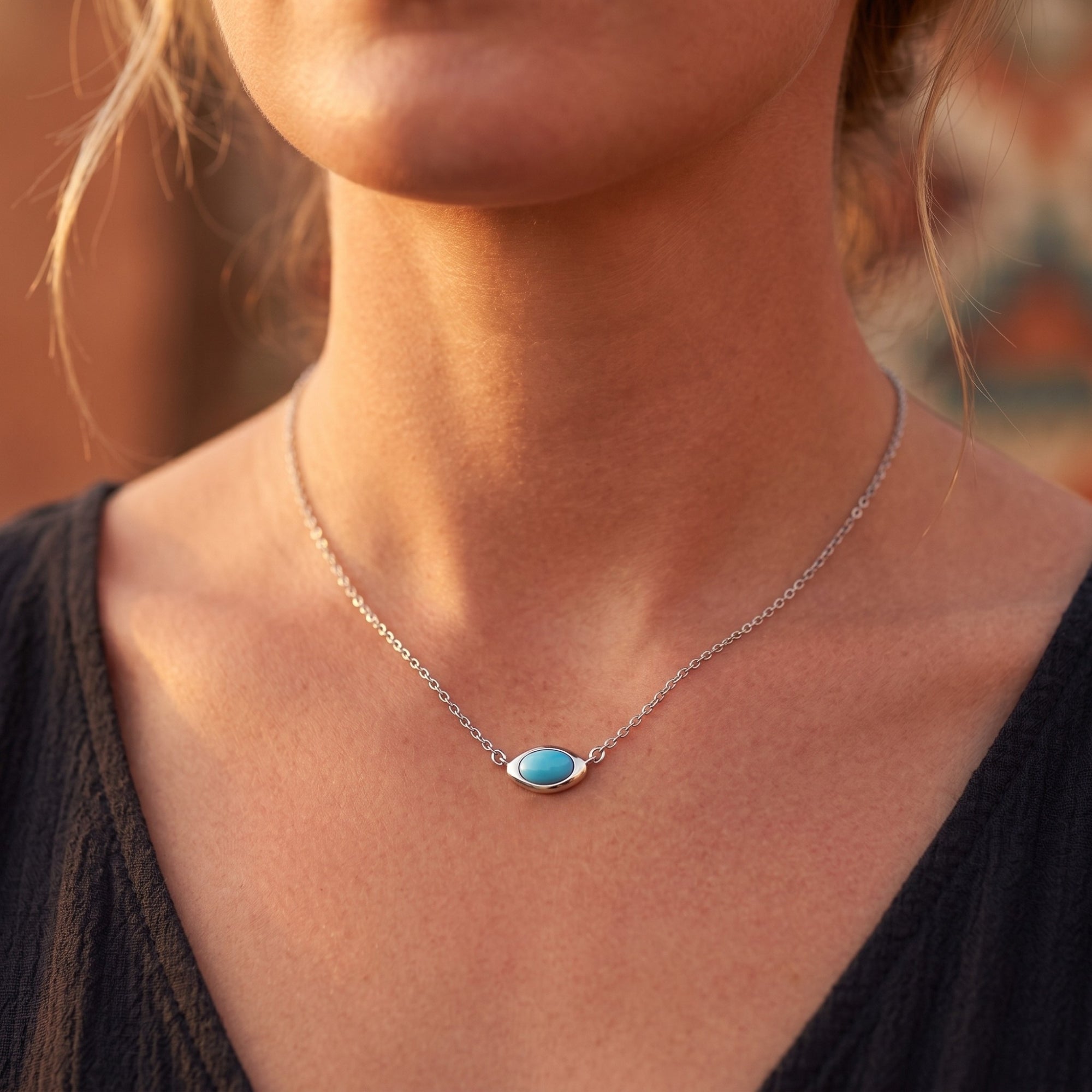 Close-up of a woman wearing a silver turquoise necklace with a horizontal bezel-set cabochon on a delicate chain.