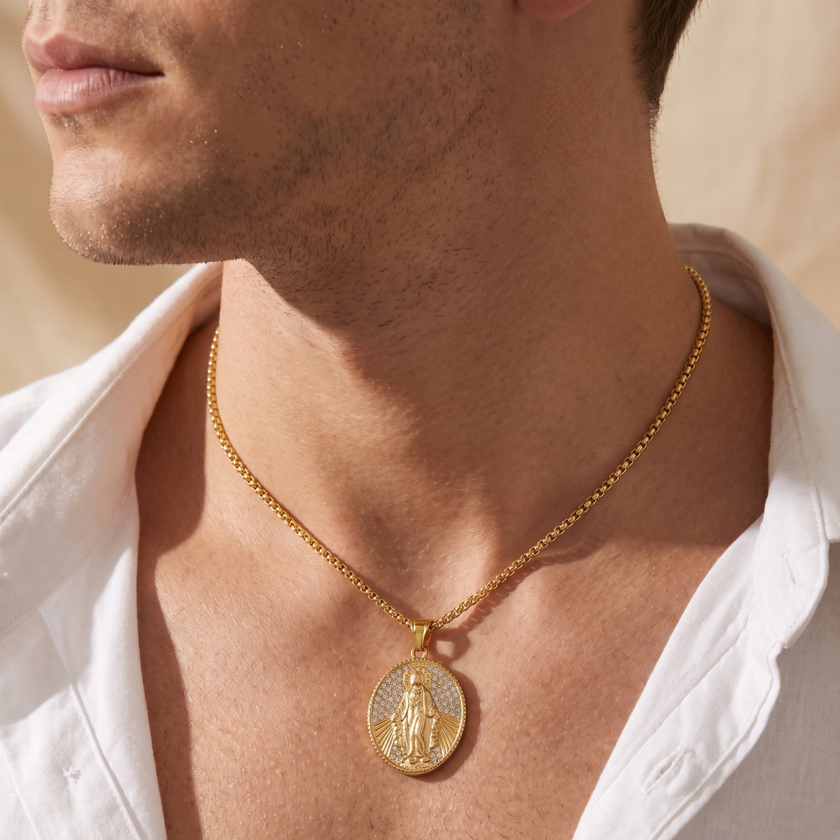 Side-angle close-up of a man wearing the gold-tone oval Miraculous Medal necklace with an open white collar.
