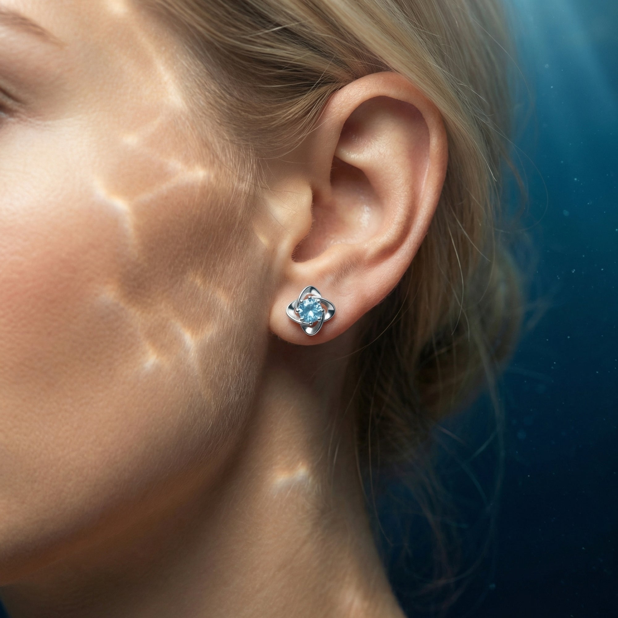 Side view of a woman wearing a round cut aquamarine stud earring in platinum with shimmering light patterns.