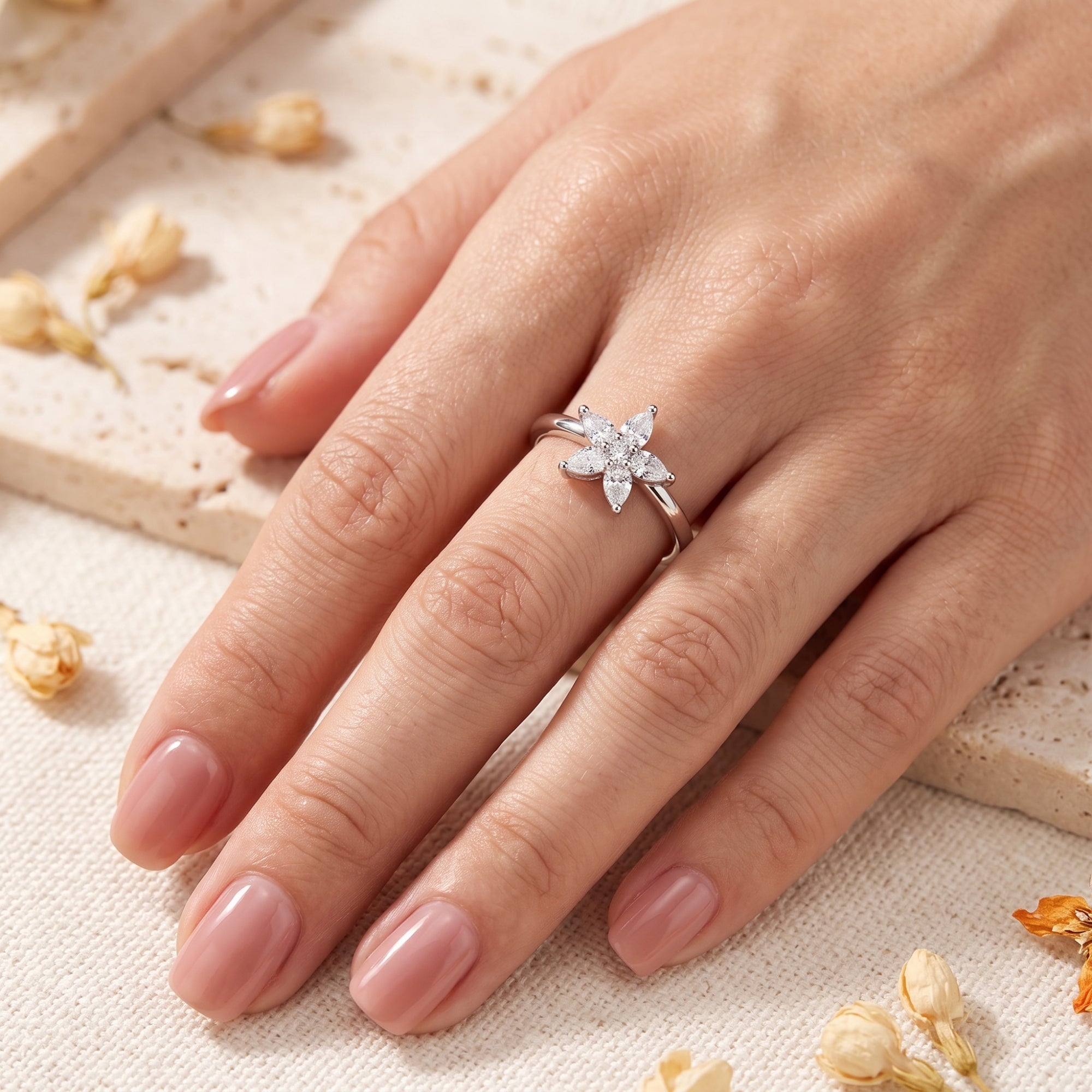 Top-down view of silver blossom ring on finger for scale.