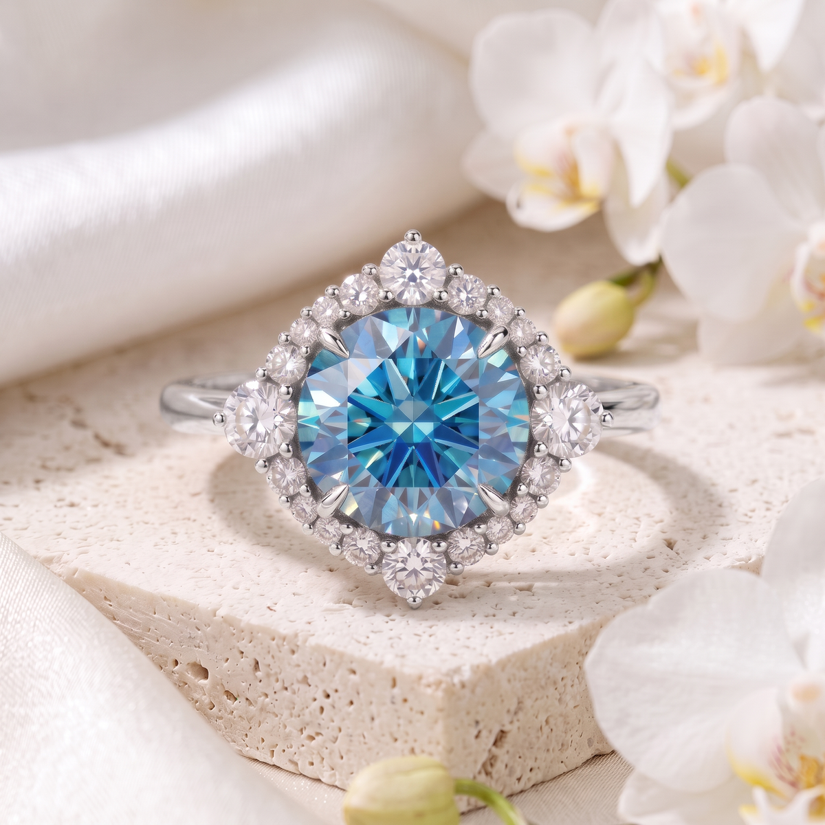 White gold round blue moissanite ring with a sparkling halo displayed on a stone surface.