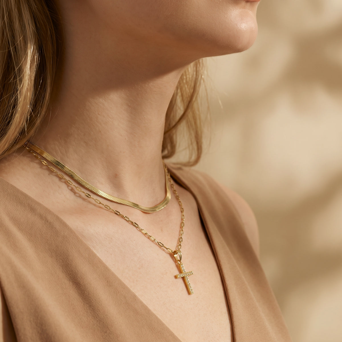 Side profile of a model wearing the gold-tone layered cross necklace across her collarbone.