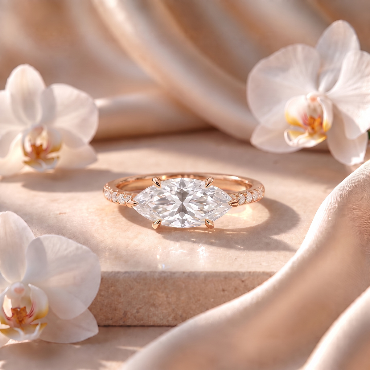 An east-west marquise moissanite engagement ring with a pavé band in rose gold.