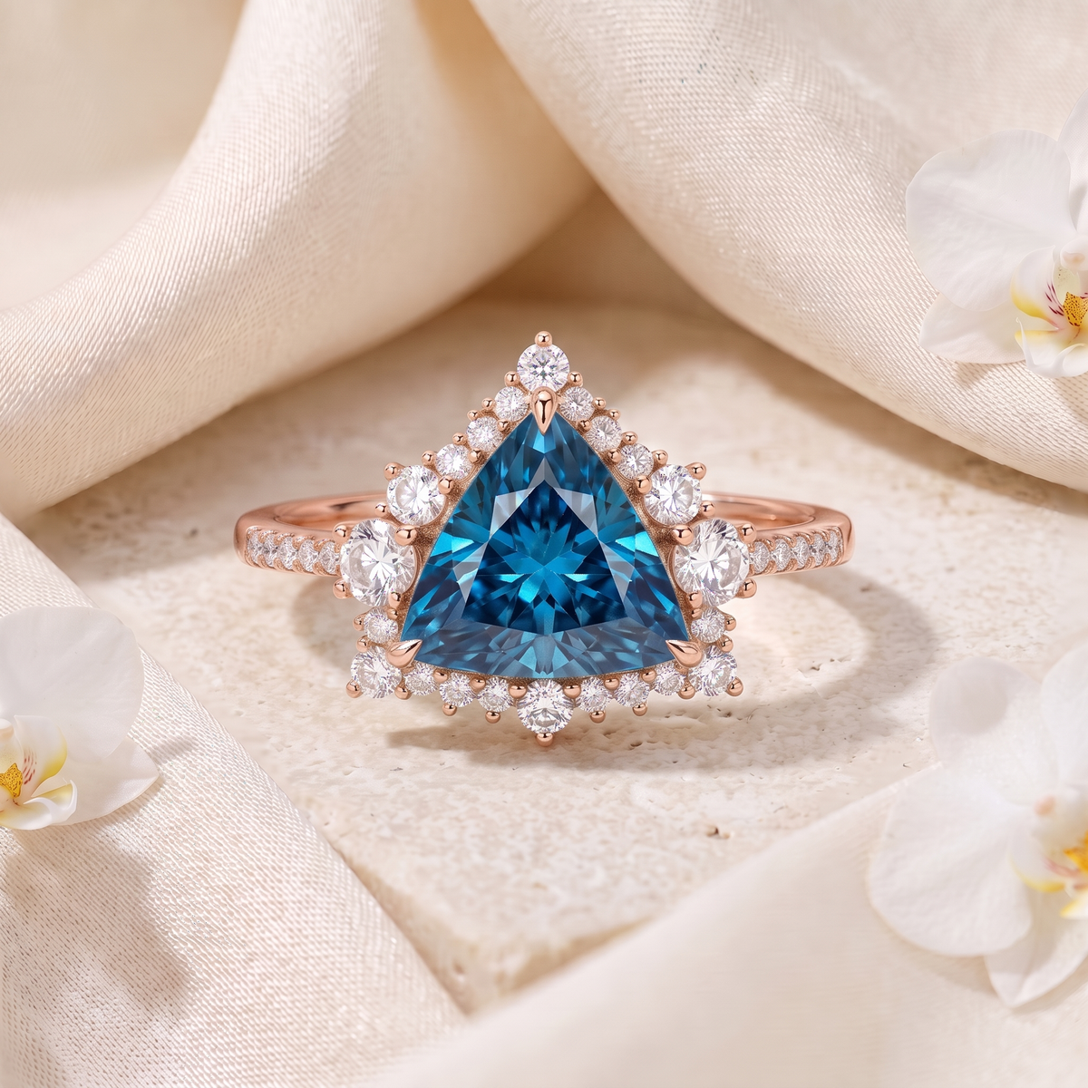 Trillion-cut blue moissanite halo engagement ring in rose gold displayed on stone with silk fabric.