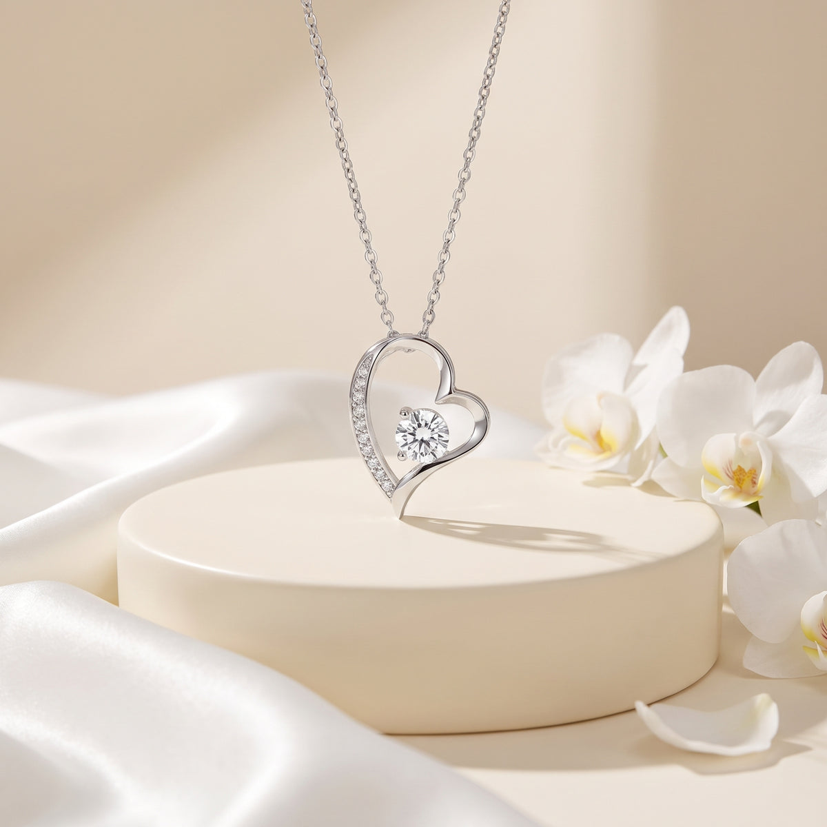 Silver open-heart pendant necklace on a pale display with flowers.