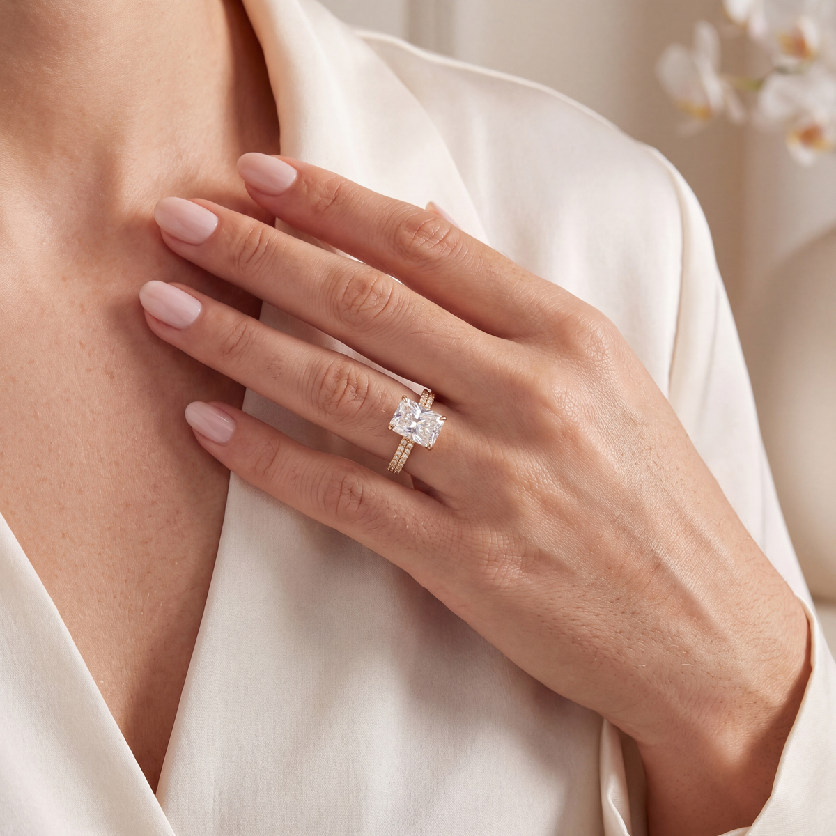 Lifestyle shot of a woman wearing the yellow gold radiant-cut moissanite ring with her hand resting on her chest.