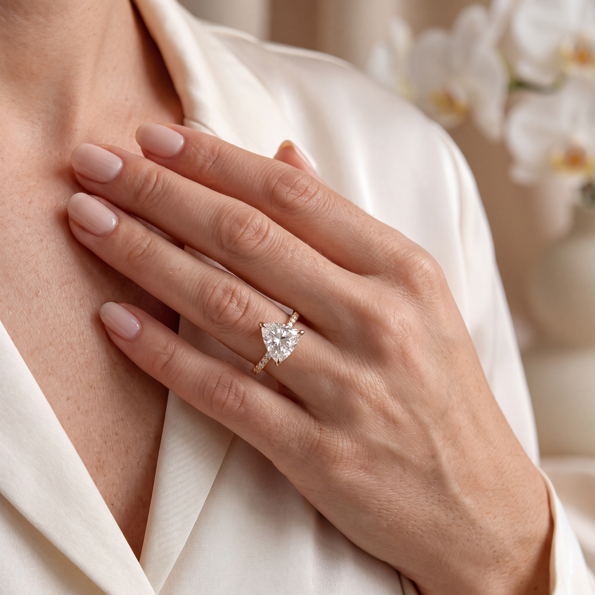 Close-up lifestyle shot of a model displaying a yellow gold trillion-cut moissanite ring on her hand.