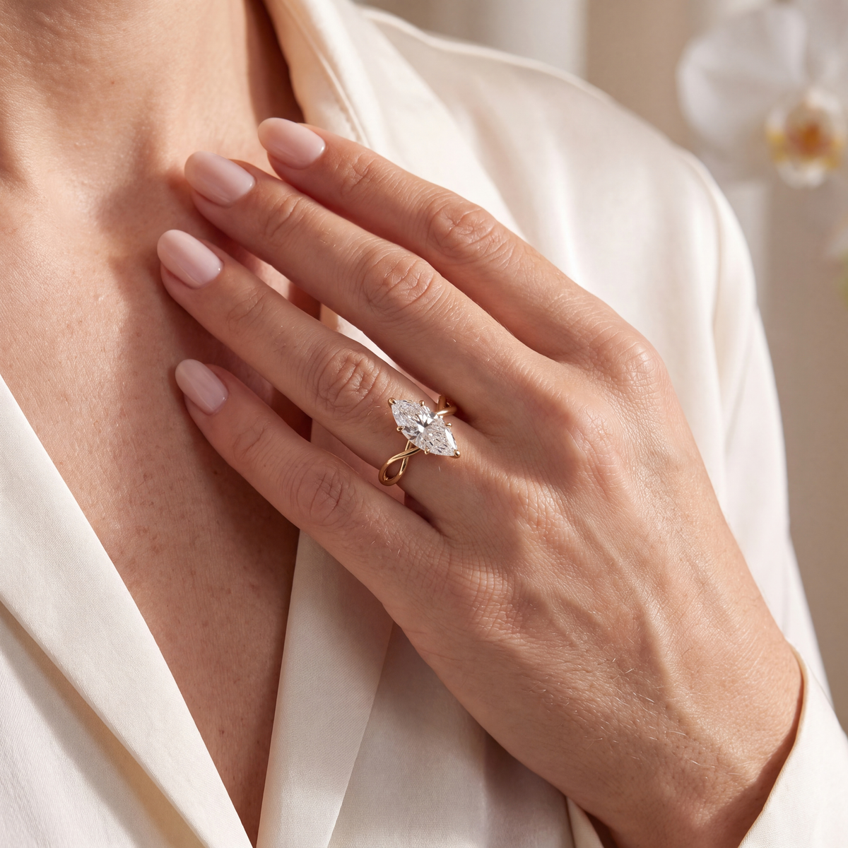 Gold marquise-cut moissanite engagement ring worn on a hand, resting on the chest.