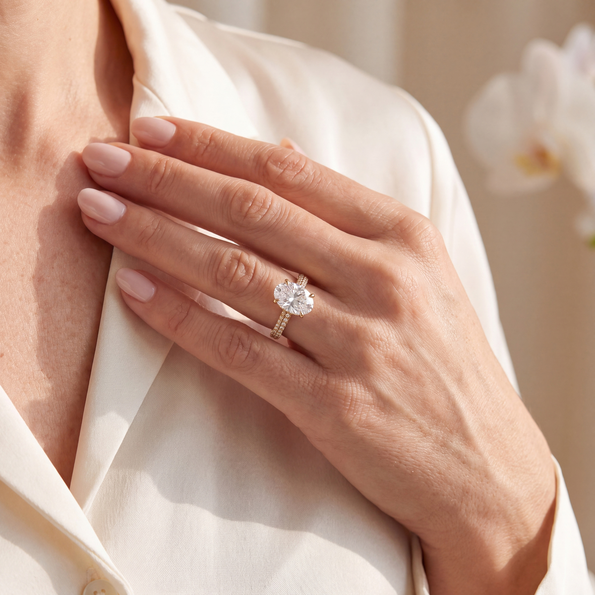 A woman wearing a yellow gold oval-cut moissanite engagement ring with a diamond-paved band.