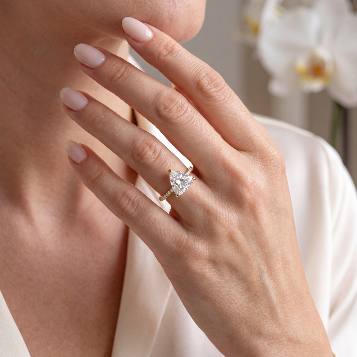 Lifestyle shot of a model resting her hand while wearing the yellow gold trillion-cut moissanite engagement ring.