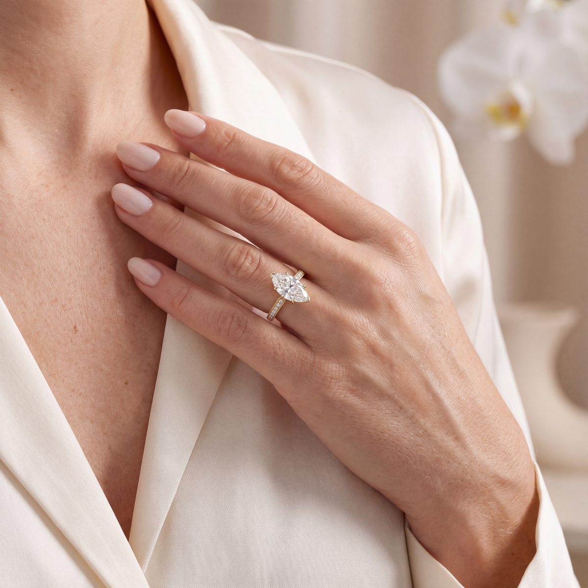 Model wearing the yellow gold marquise moissanite engagement ring resting her hand near her collarbone.