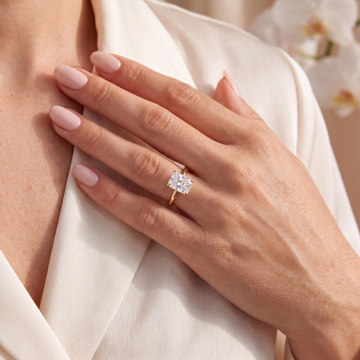 Close-up of a model wearing a yellow gold radiant-cut moissanite engagement ring near her lapel.
