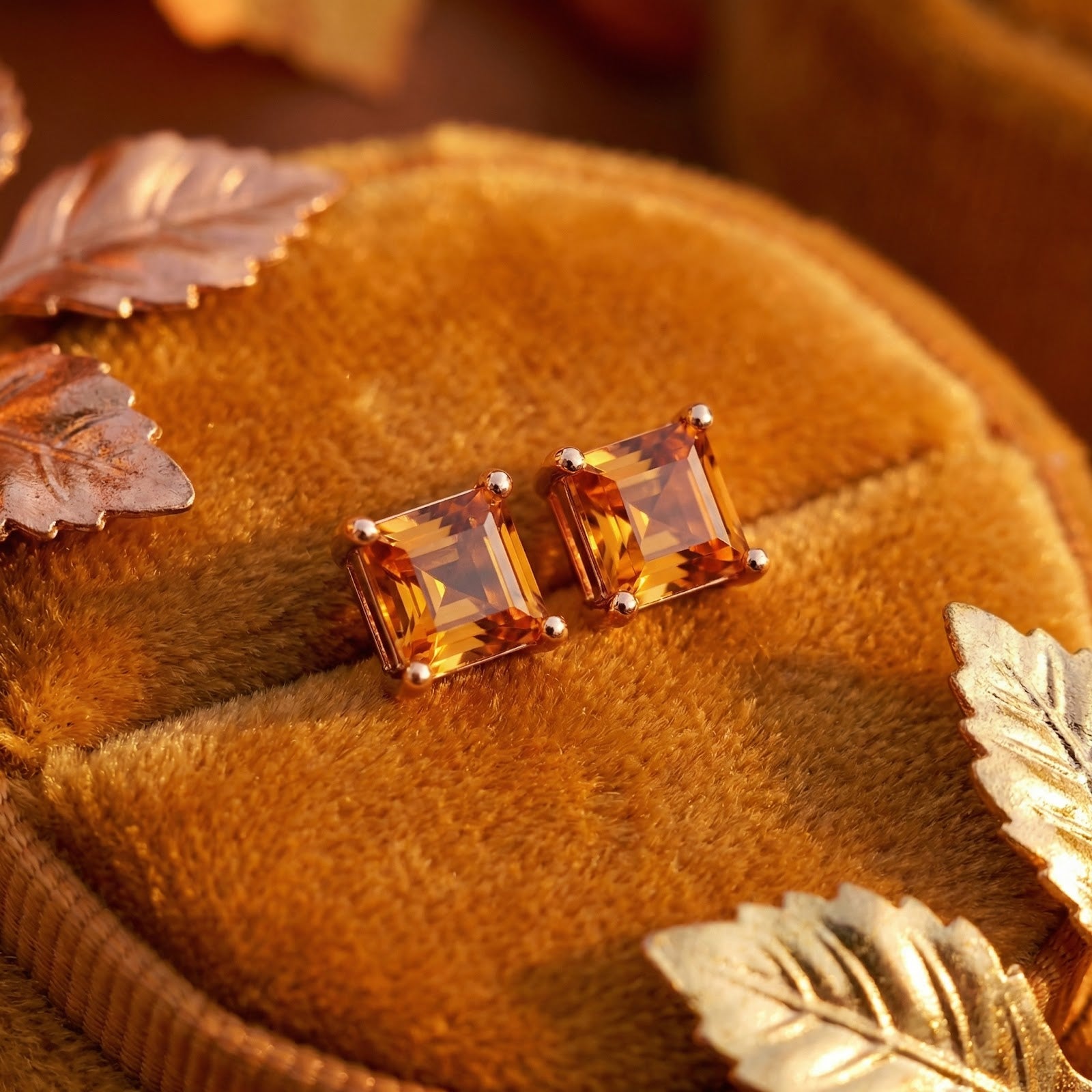 Square-cut simulated topaz stud earrings in 18K rose gold vermeil styled on velvet with autumn leaves.