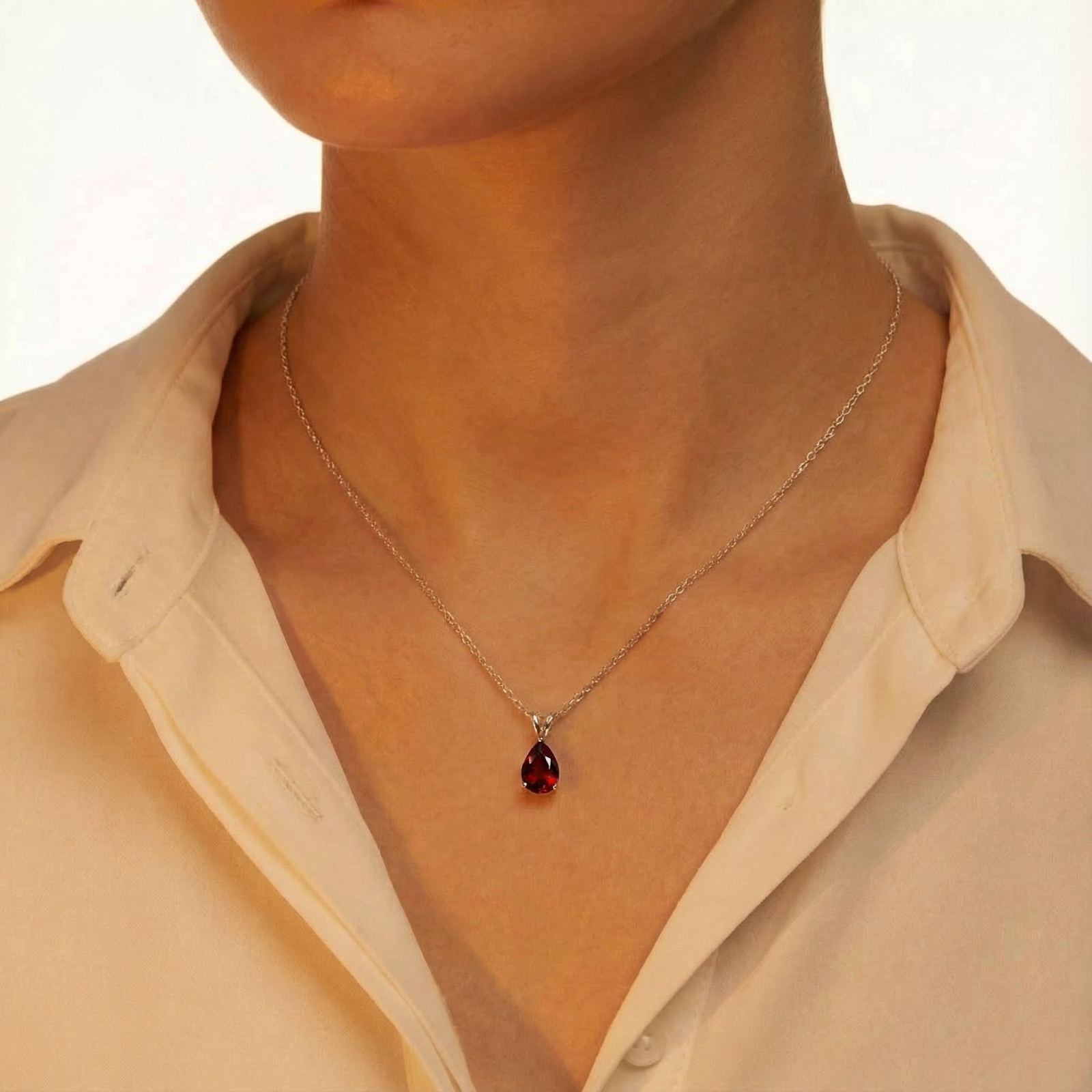 Model wearing the pear cut simulated garnet necklace in sterling silver with a white button-down shirt.