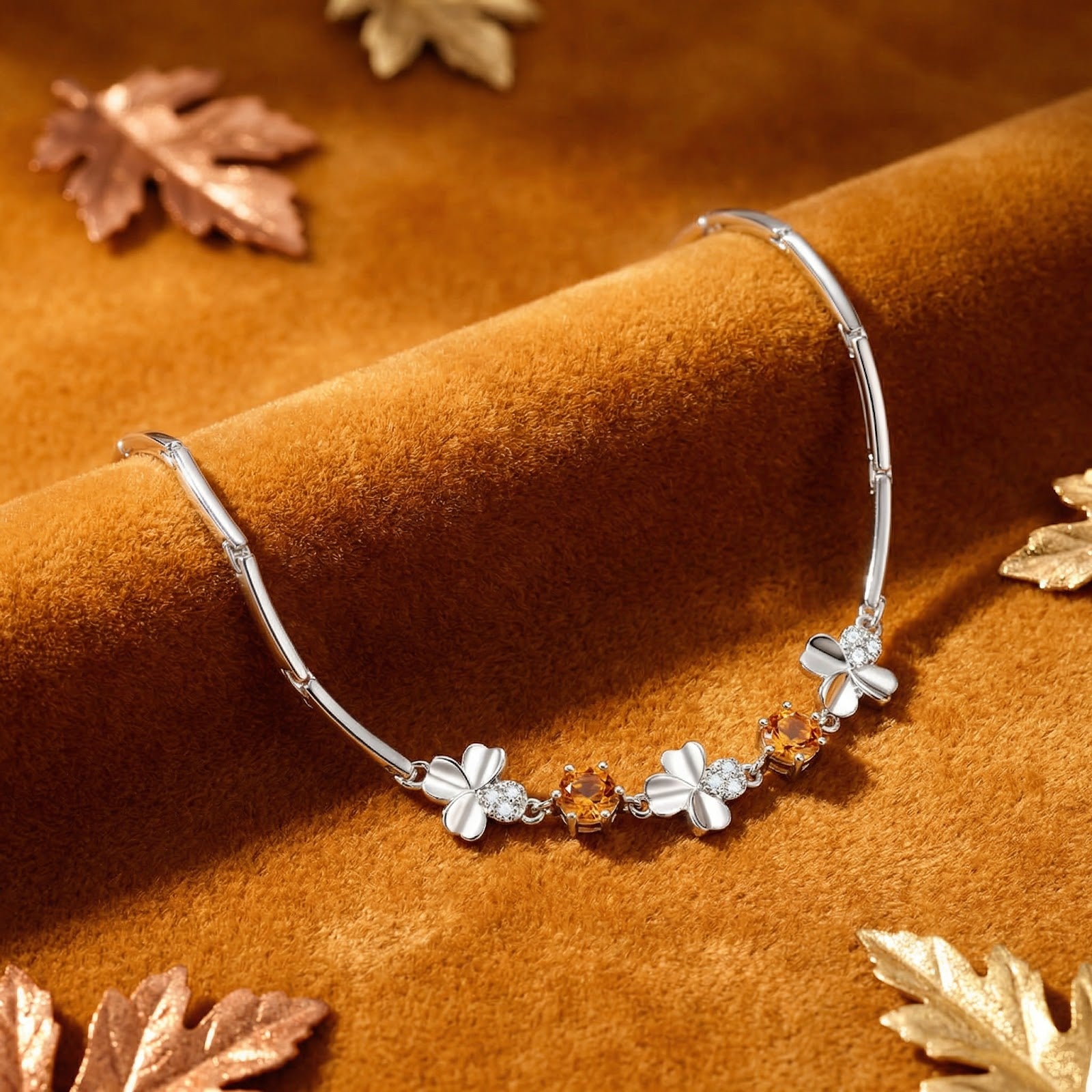Macro view of sterling silver clover charms and round honey simulated topaz stones on a brown velvet surface.