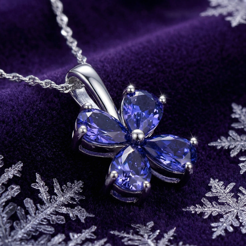 Macro view of the Sidraea Clover pendant's pear-cut simulated tanzanite stones and silver setting with snowflakes.