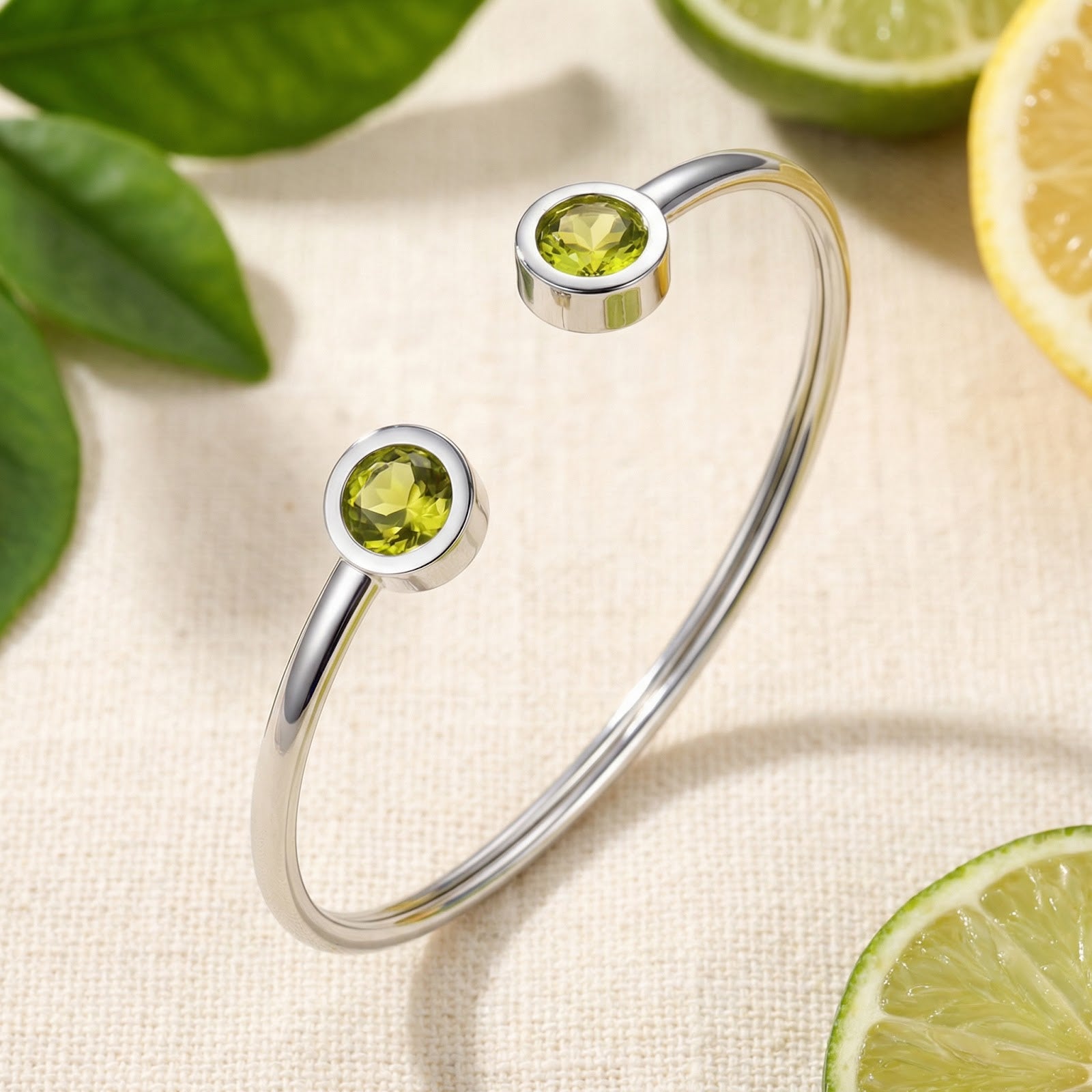 Silver stainless steel Peridara cuff bracelet with round simulated peridots on a styled citrus background.