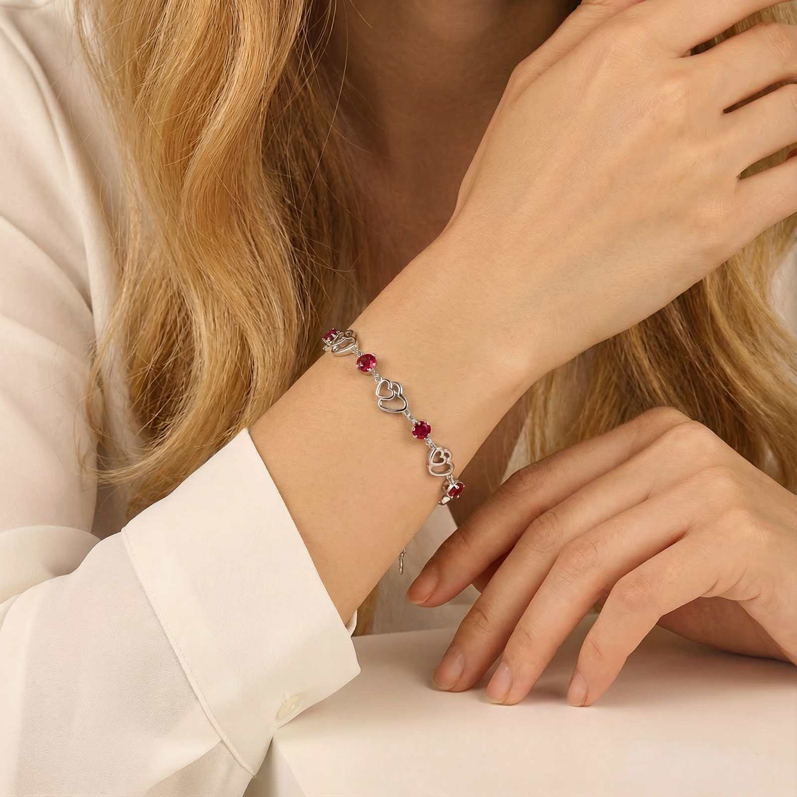 Close-up of the sterling silver heart bracelet with red simulated rubies on a model's wrist.