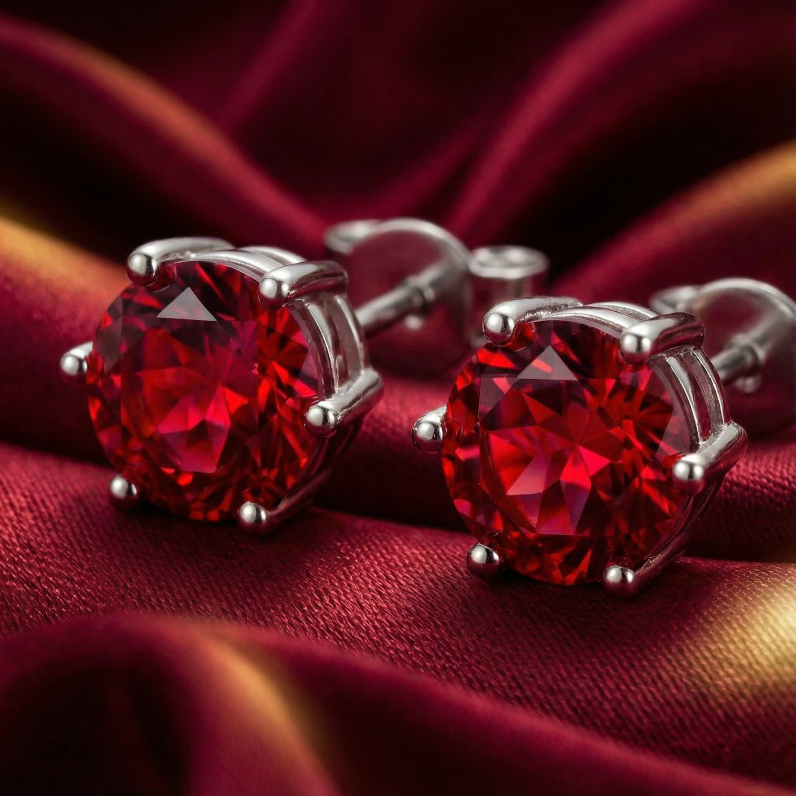 Macro view of precision-cut round simulated ruby studs in rhodium-plated sterling silver settings.