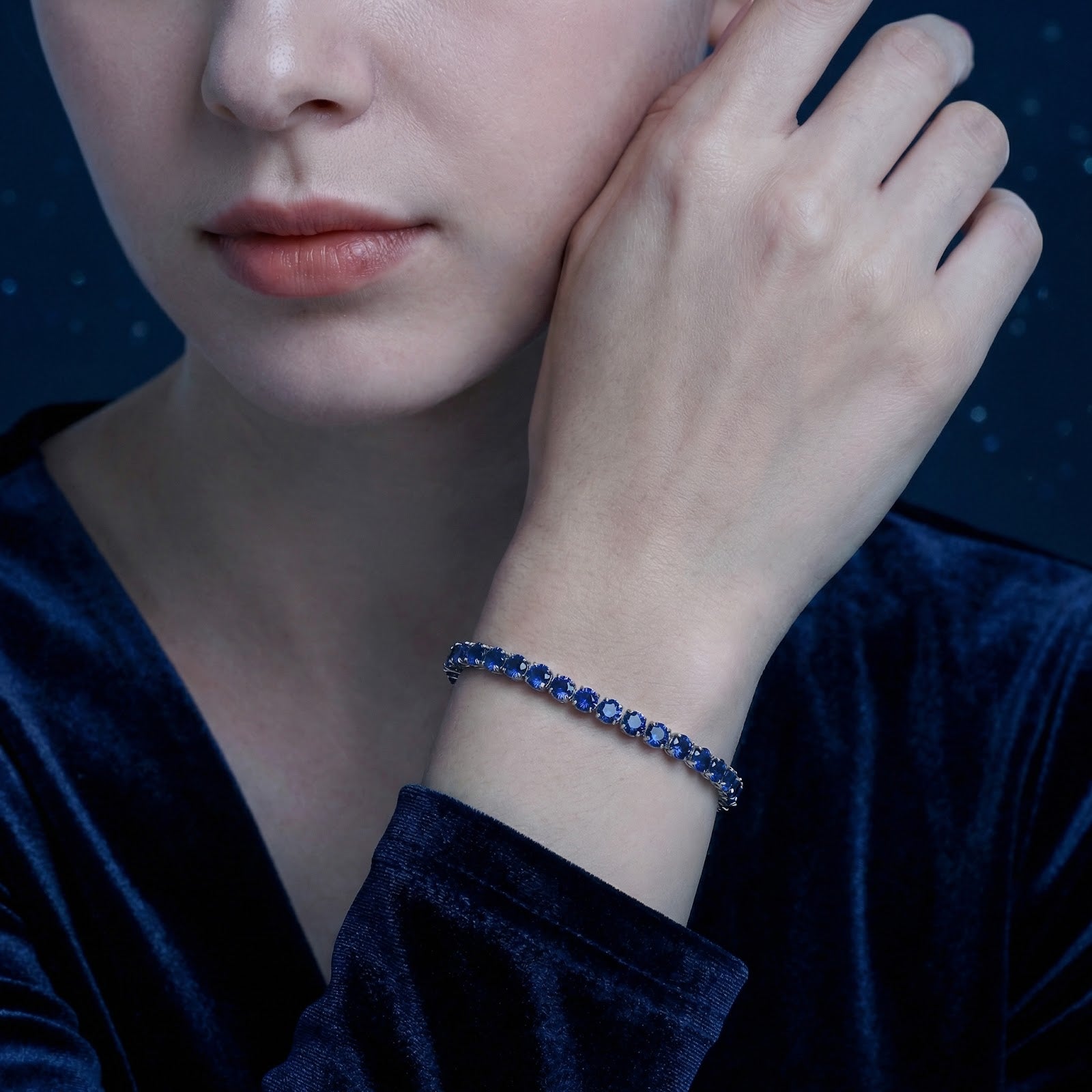 Woman wearing the silver stainless steel tennis bracelet featuring round royal blue simulated sapphires.