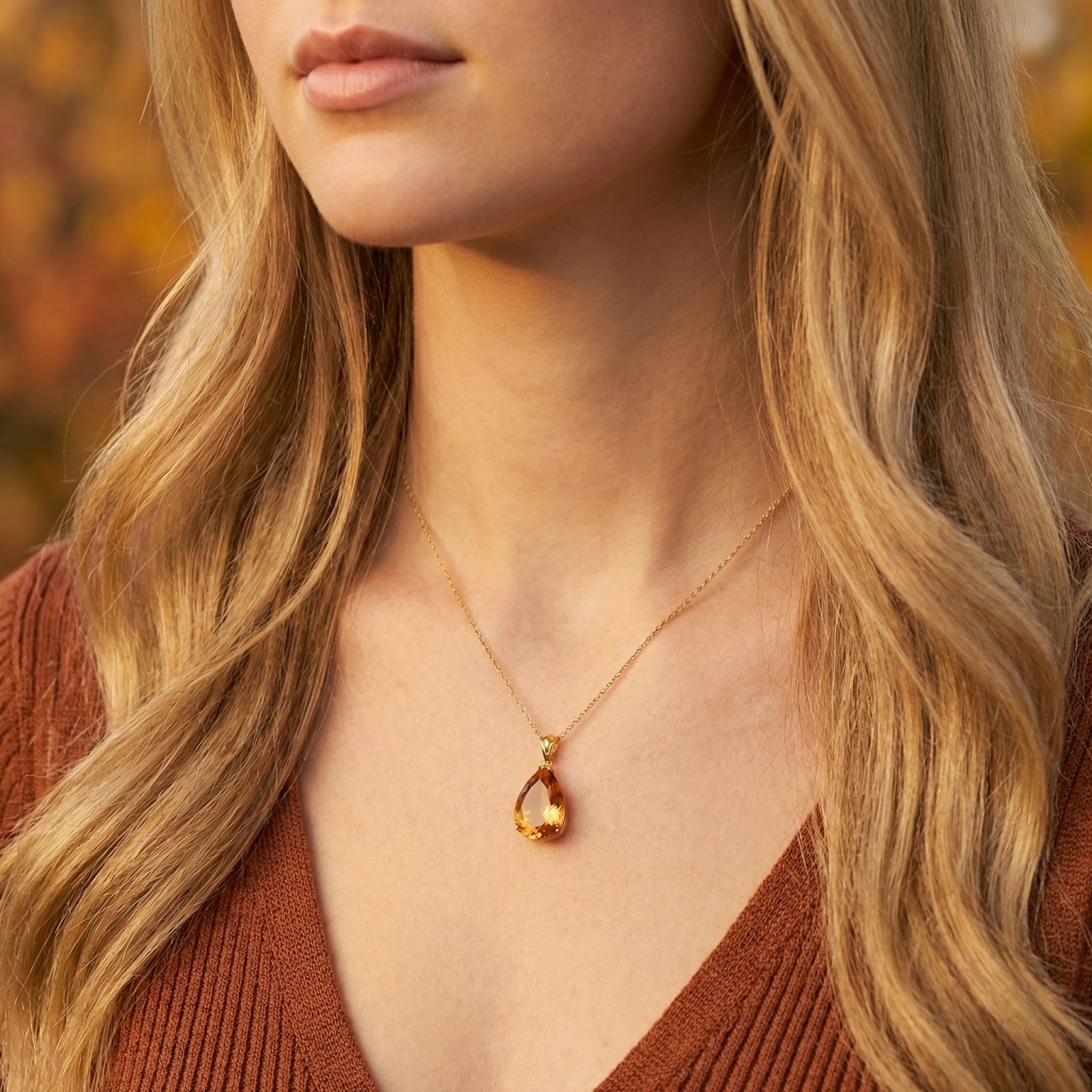 Front view of a model wearing the 18K gold vermeil Amberine necklace with a teardrop simulated topaz pendant.