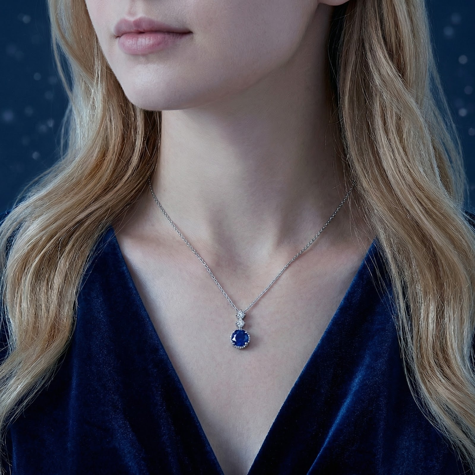 Royal blue simulated sapphire pendant on a sterling silver chain worn by a model in a velvet dress.