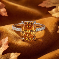 Radiant-cut simulated topaz ring with a pavé band on velvet with autumn leaves, crafted in solid gold.