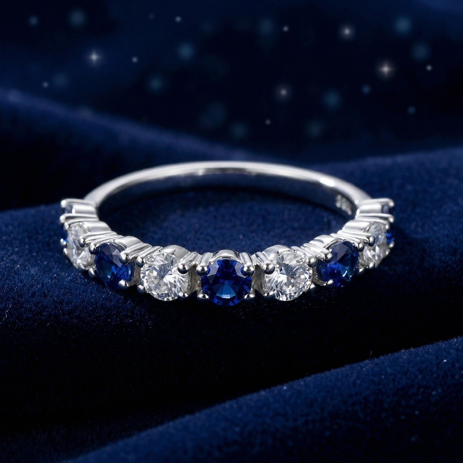 Thalissara row ring in S925 sterling silver with round cut simulated sapphires on a blue velvet background.