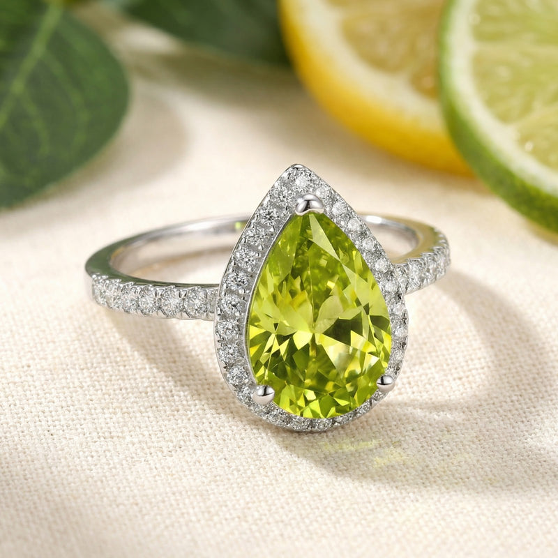 Angled view of the pear-cut simulated peridot ring with a pavé sterling silver band and halo setting.