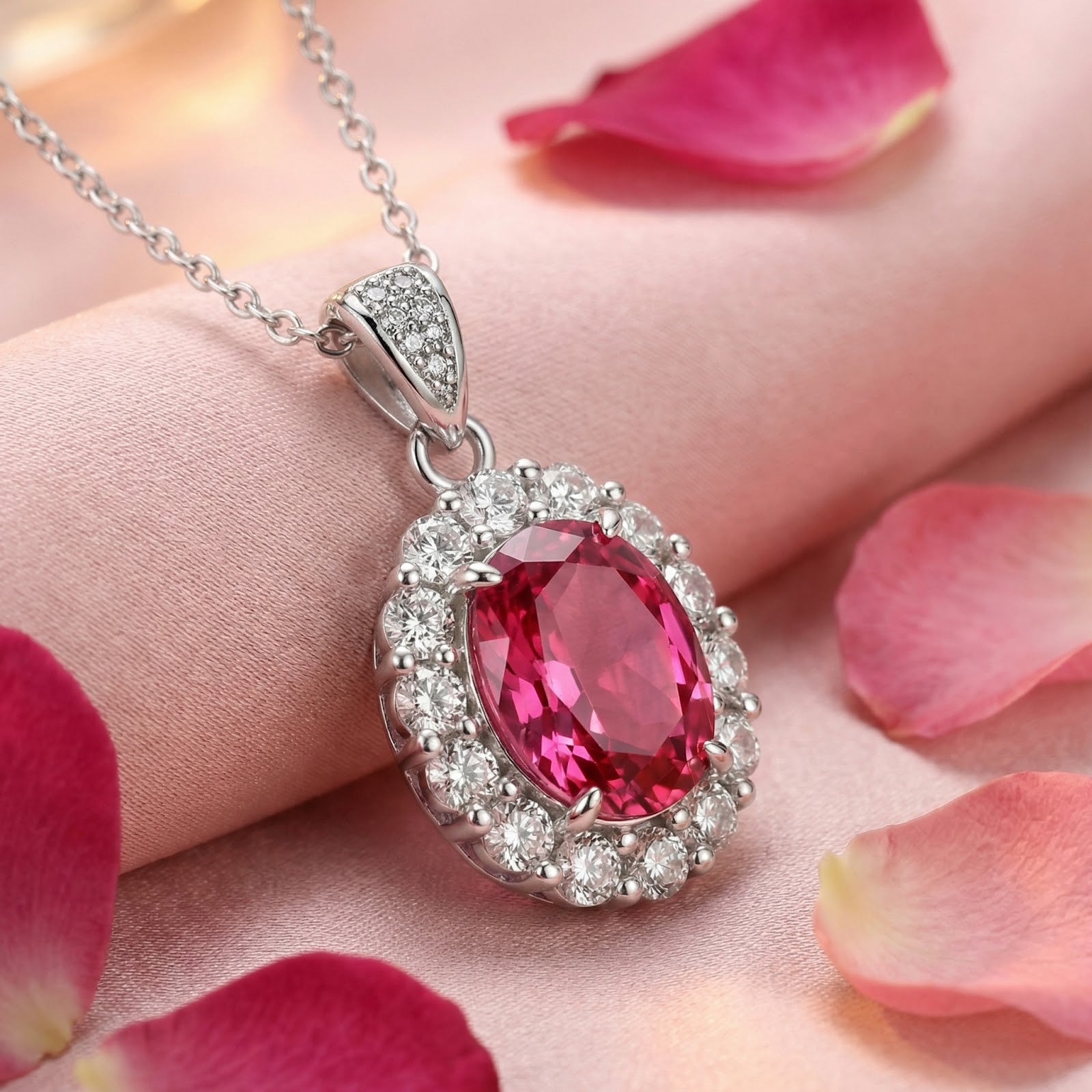 Close-up view of the oval pink tourmaline and clear stone halo pendant on a sterling silver chain.