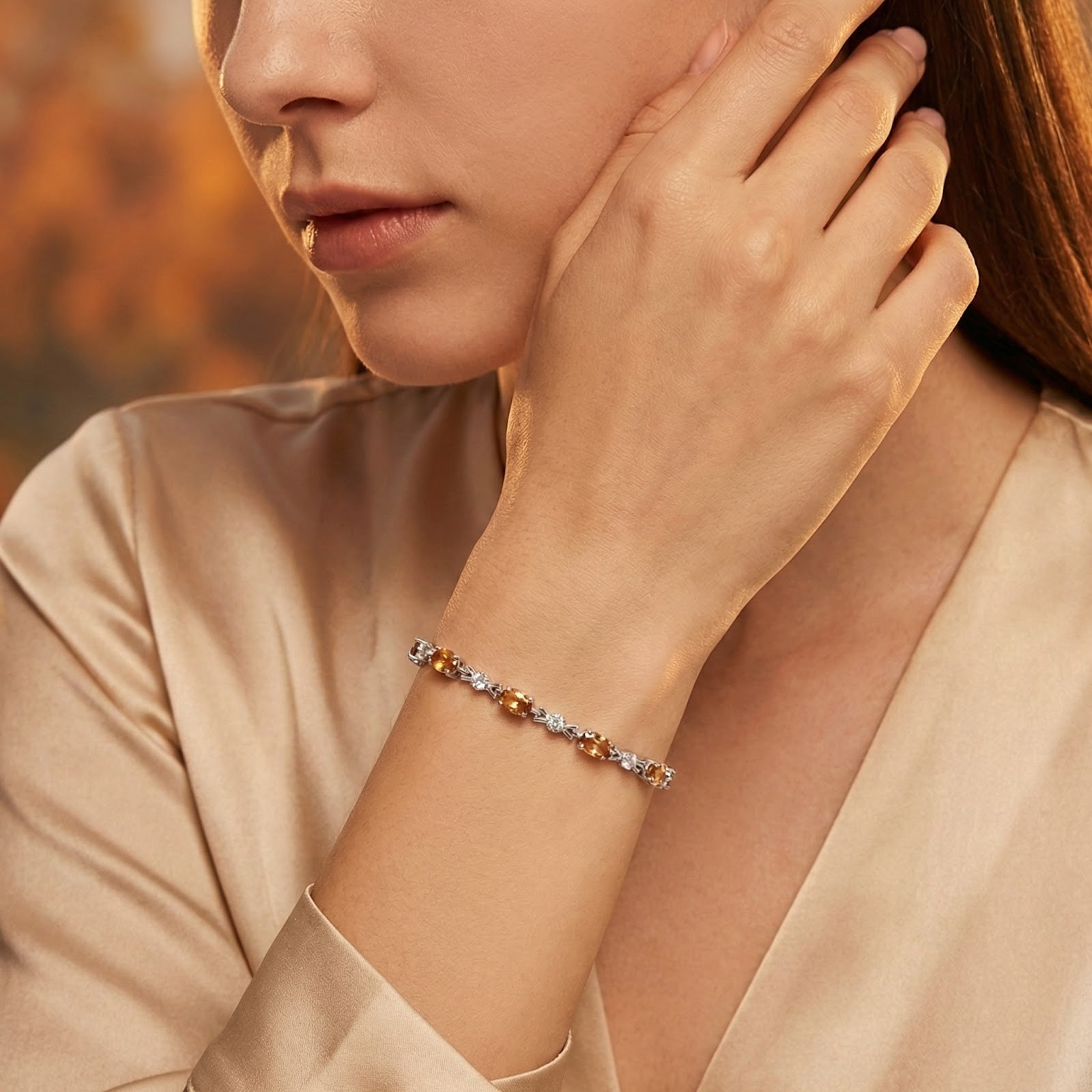 Sterling silver station bracelet with oval simulated topaz stones worn on a woman's wrist.