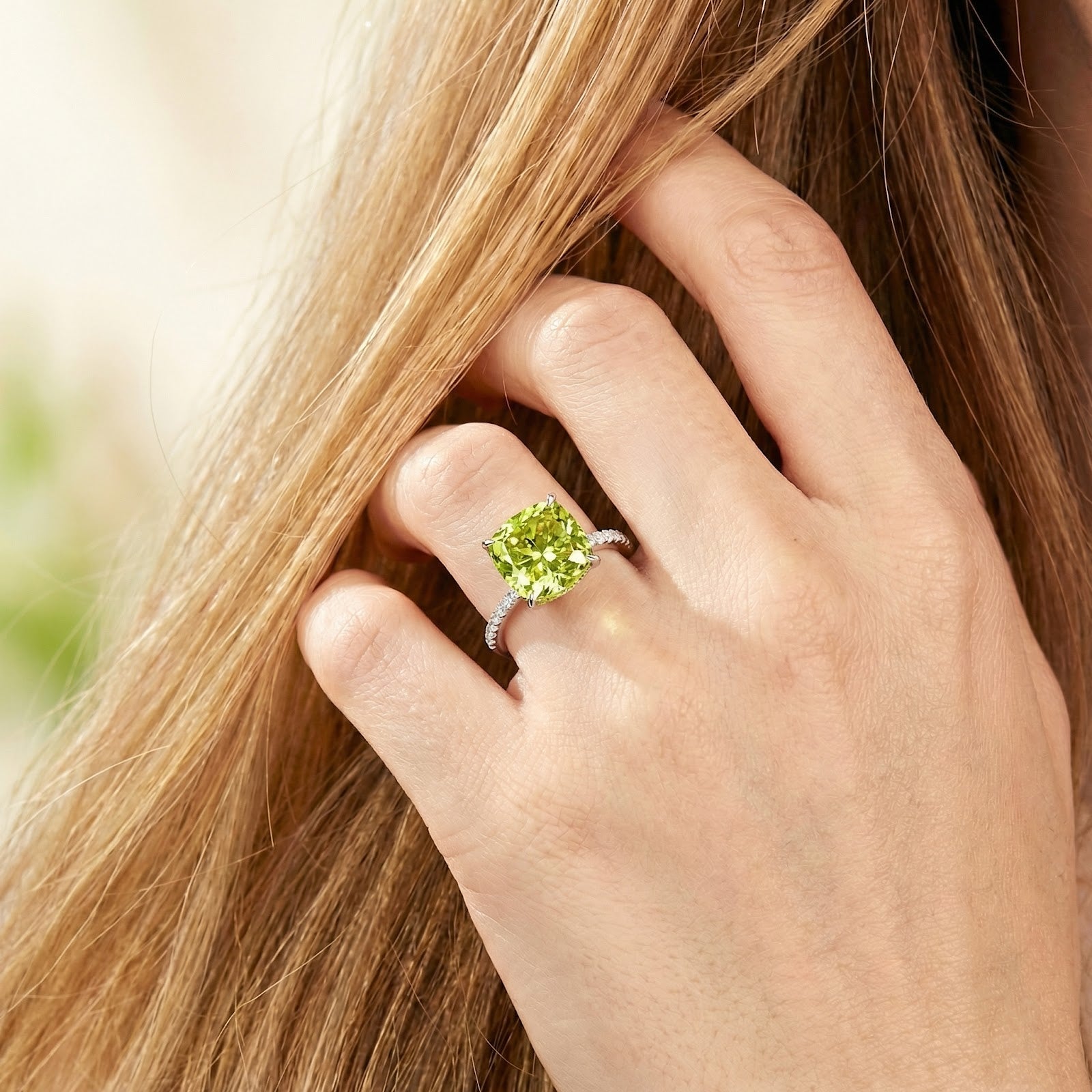 Cushion-cut simulated peridot ring in S925 sterling silver worn on a model's hand against her hair.