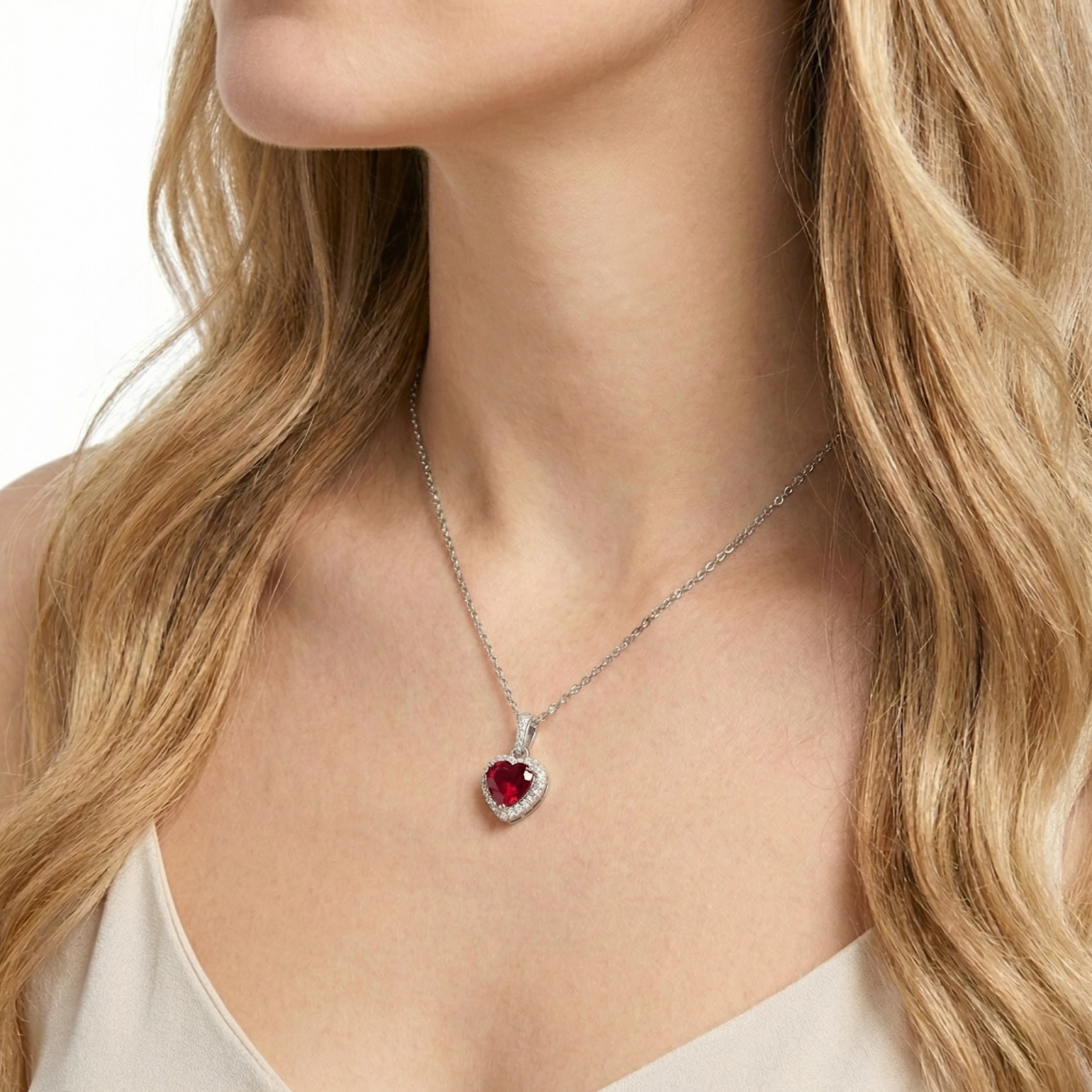 Side view of a woman wearing a heart-cut simulated ruby halo necklace in sterling silver.