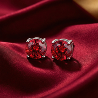 Round cut simulated ruby stud earrings in sterling silver settings on a red silk background.