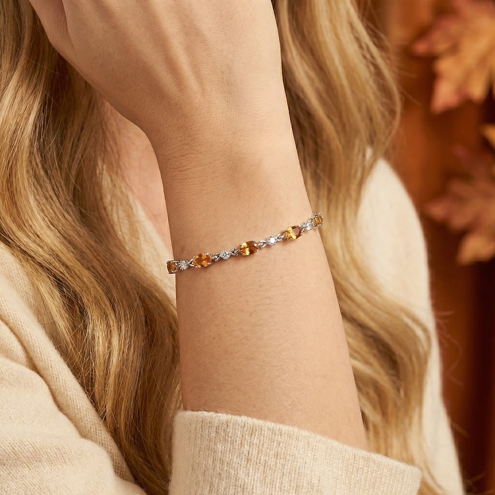 Woman wearing the sterling silver Marissella station bracelet with honey-colored oval simulated topaz stones.