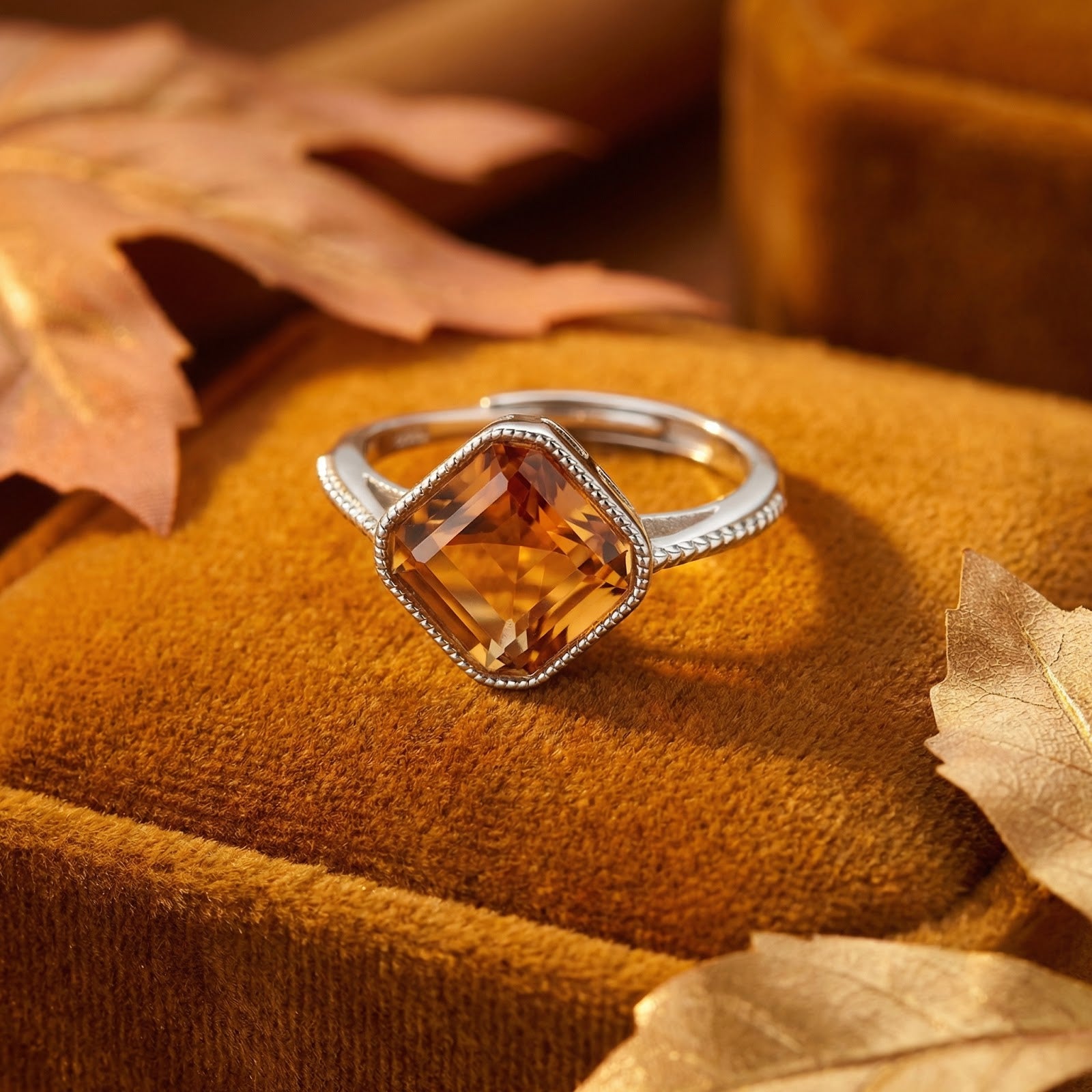 Cushion-cut honey gold simulated topaz ring in S925 sterling silver on a velvet box with autumn leaves.
