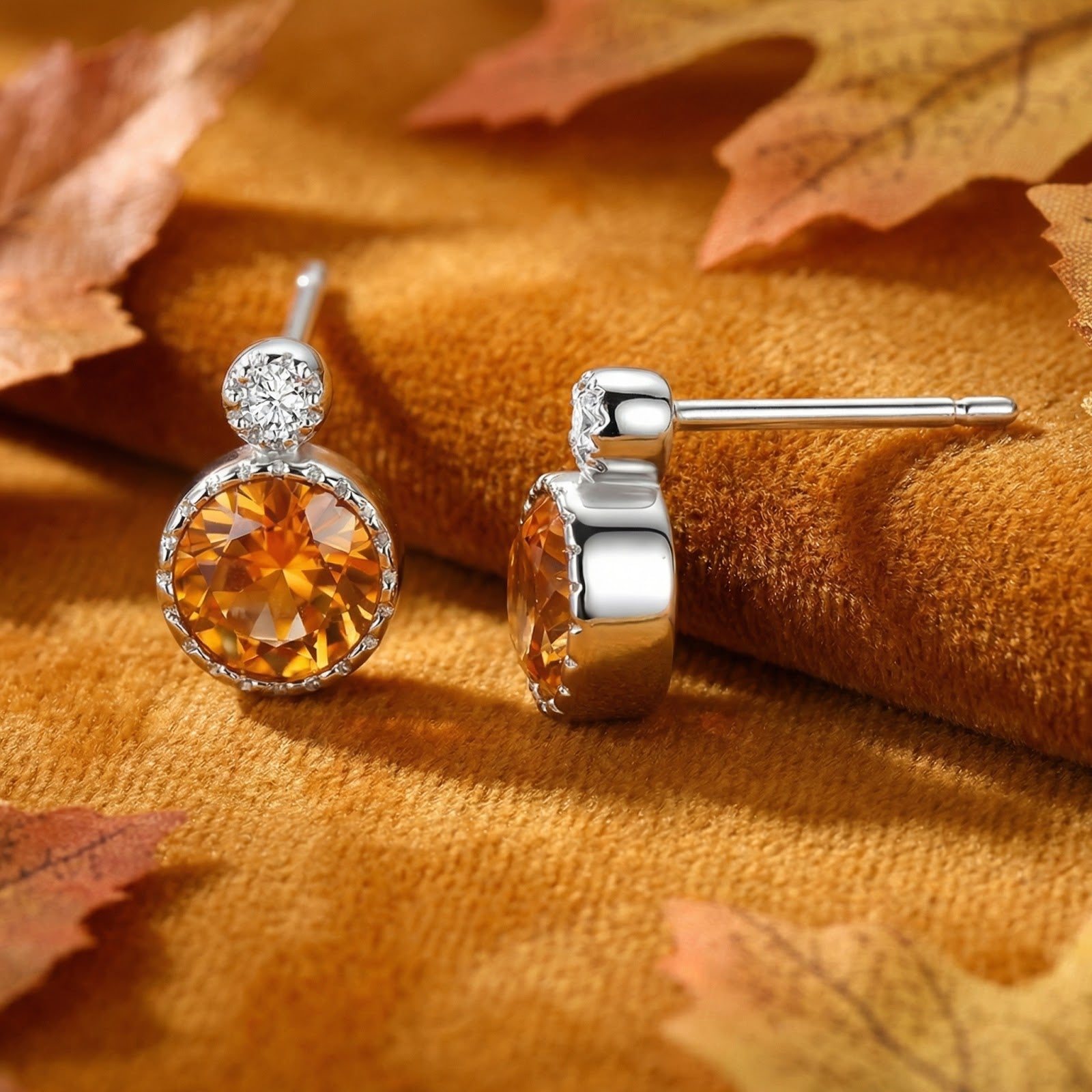 Front and side view of round-cut simulated topaz earrings in sterling silver, styled with fall leaves on velvet.