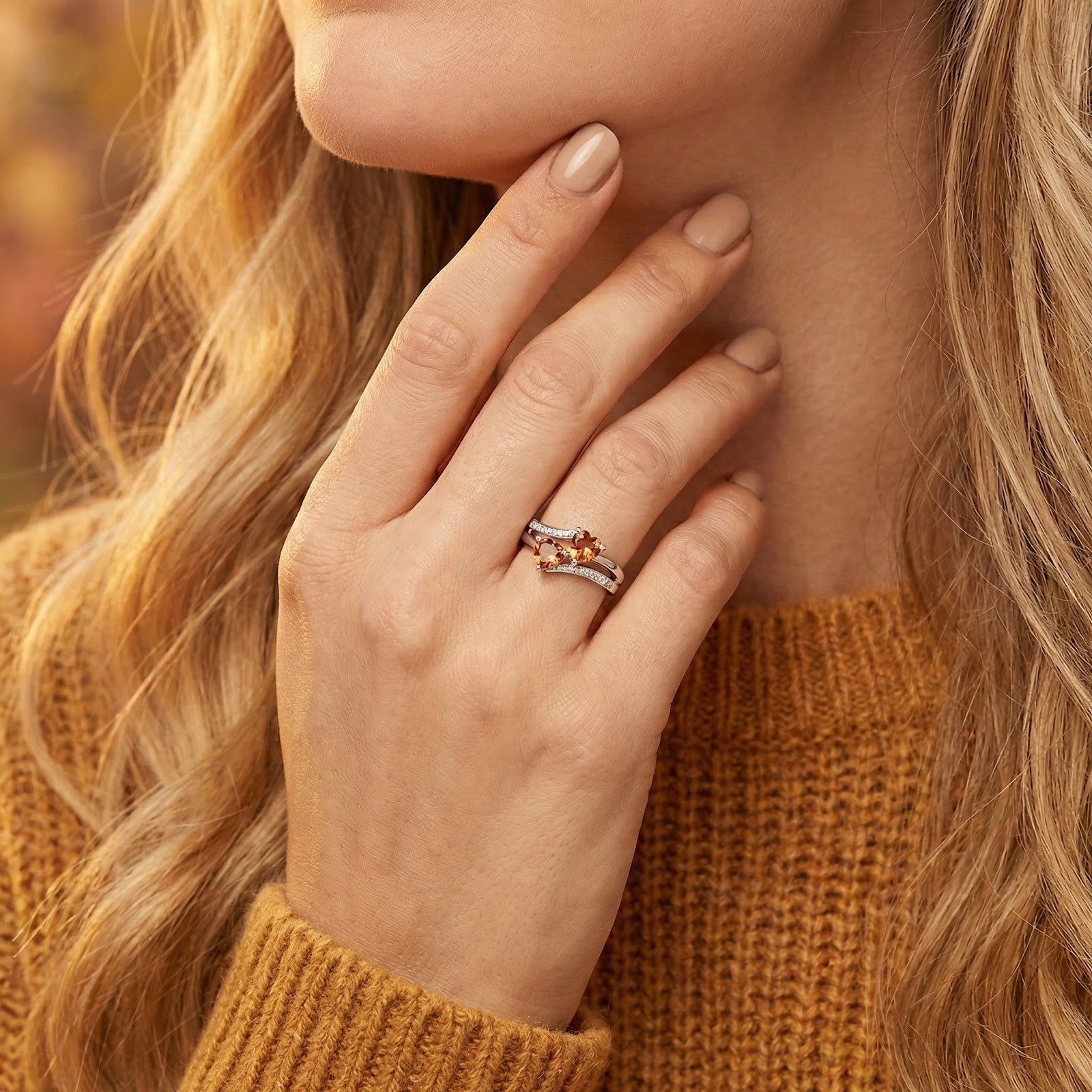 Marisara heart ring in S925 sterling silver with honeyed simulated topaz worn on a model's hand with a yellow sweater.