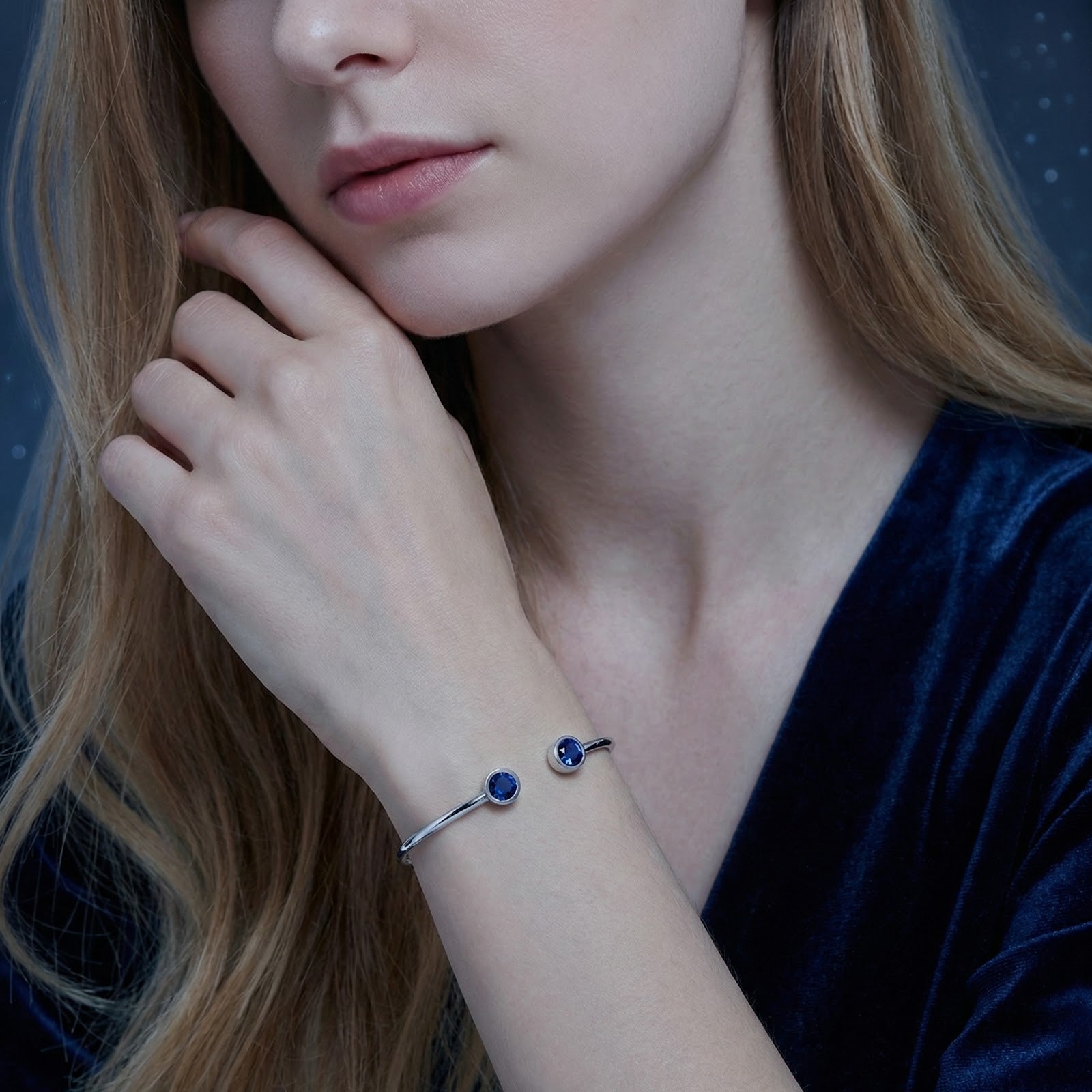 Model wearing the silver stainless steel Verian bangle with blue simulated sapphires on her wrist.