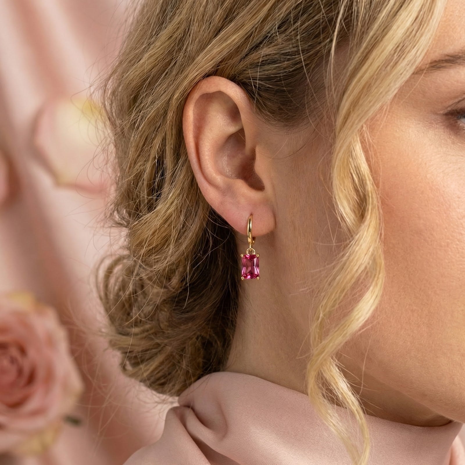 Woman wearing a gold vermeil hoop earring with a vivid emerald-cut pink tourmaline drop.