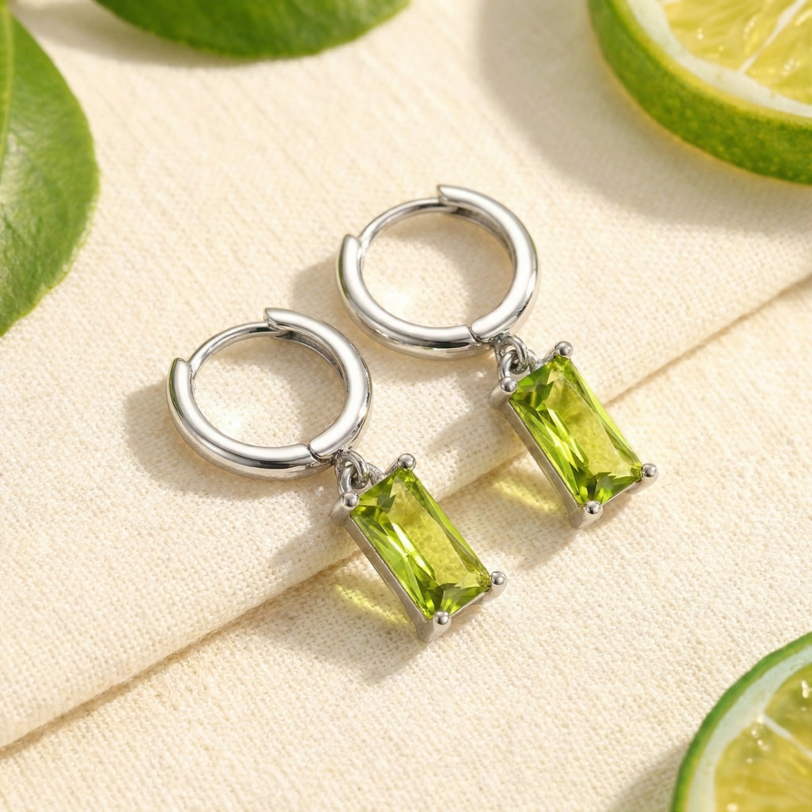 S925 sterling silver Lunaris hoop earrings with emerald-cut simulated peridot drops on a lifestyle lime background.