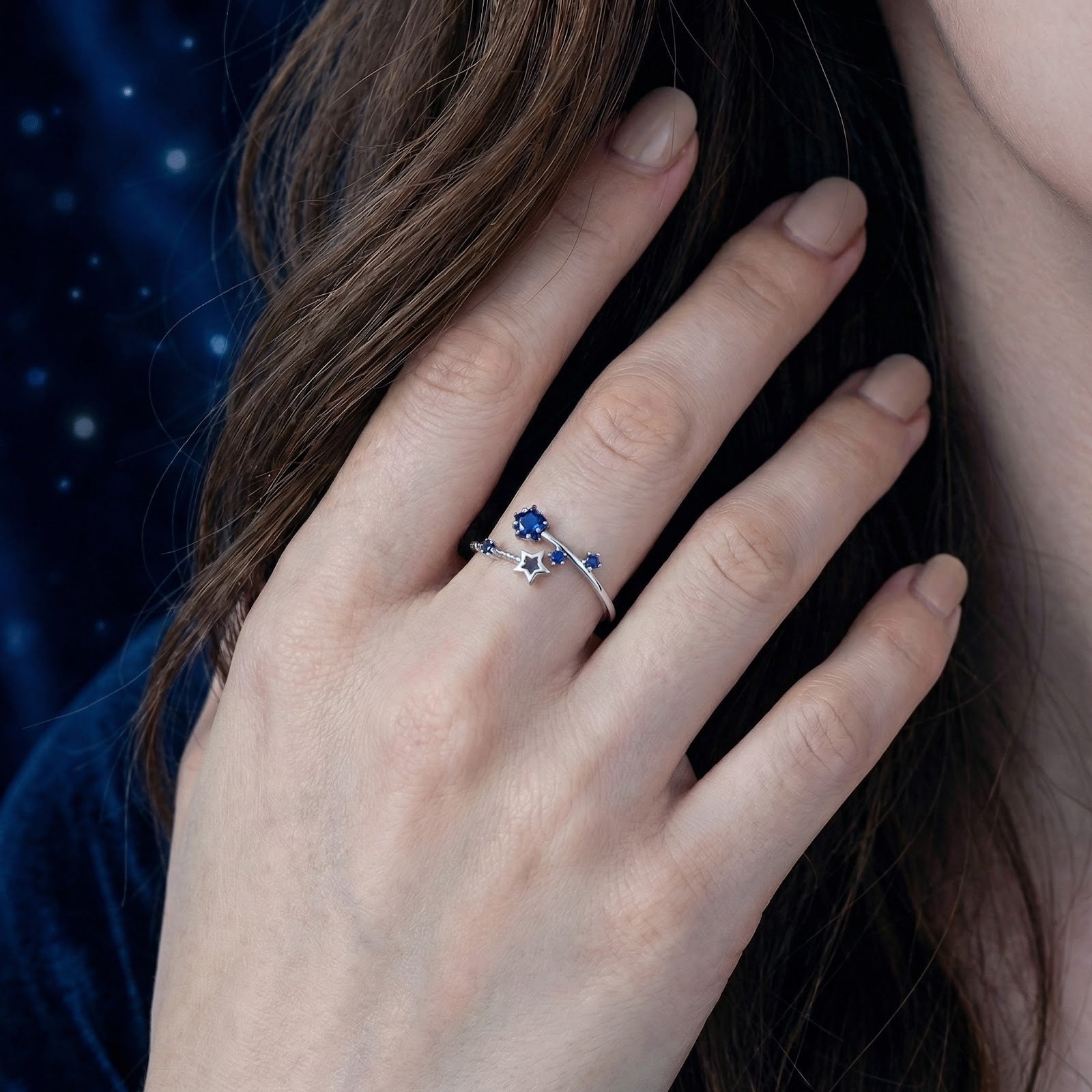 Model wearing the silver Orionis star ring with blue simulated sapphire stones on her ring finger.
