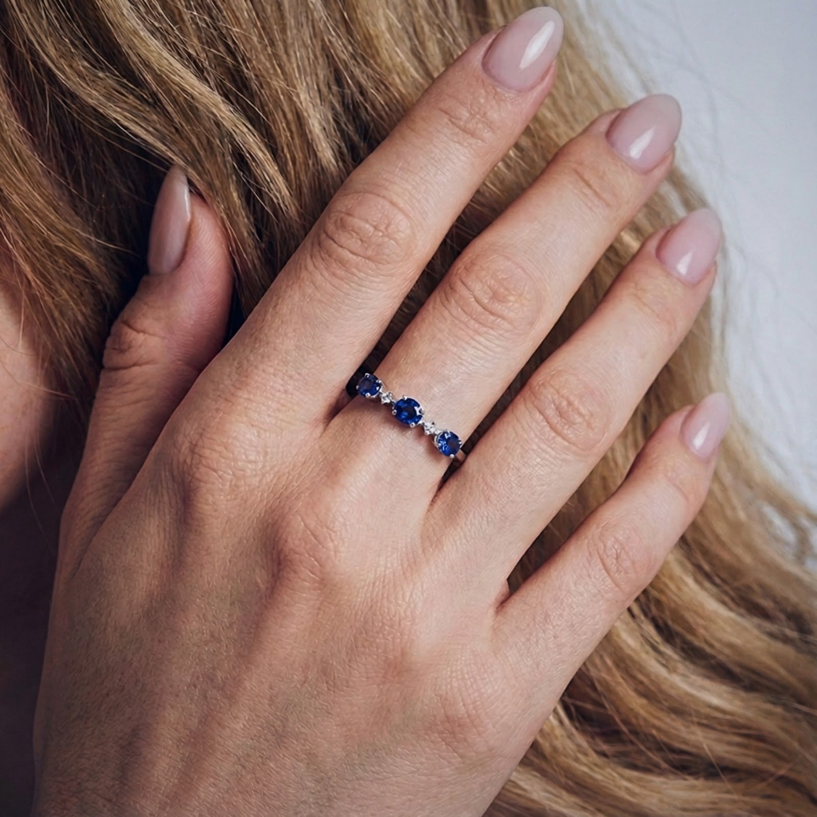 Top-down view of the Nerisara S925 sterling silver ring with blue sapphires worn on a woman's hand.