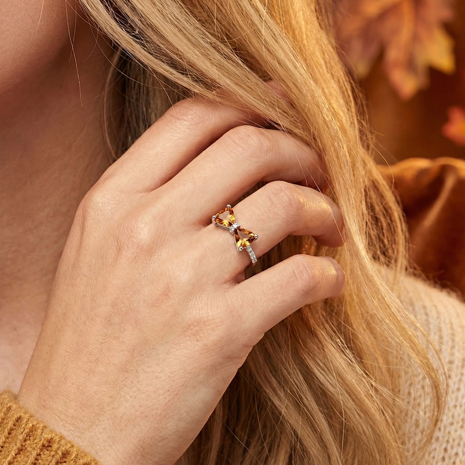Close-up of a woman's hand wearing the sterling silver bow ring with trillion-cut honey topaz stones.