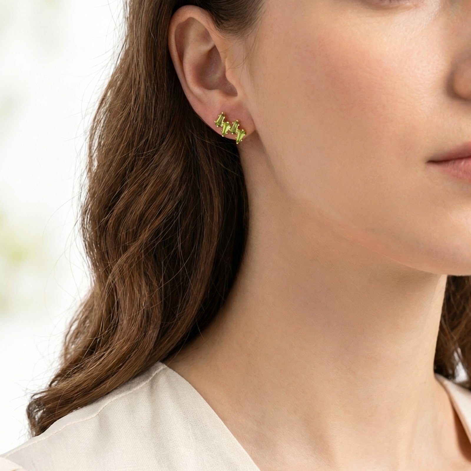 Model wearing the Zephyraea Vine earring in 18K gold vermeil with vibrant green simulated peridot stones.
