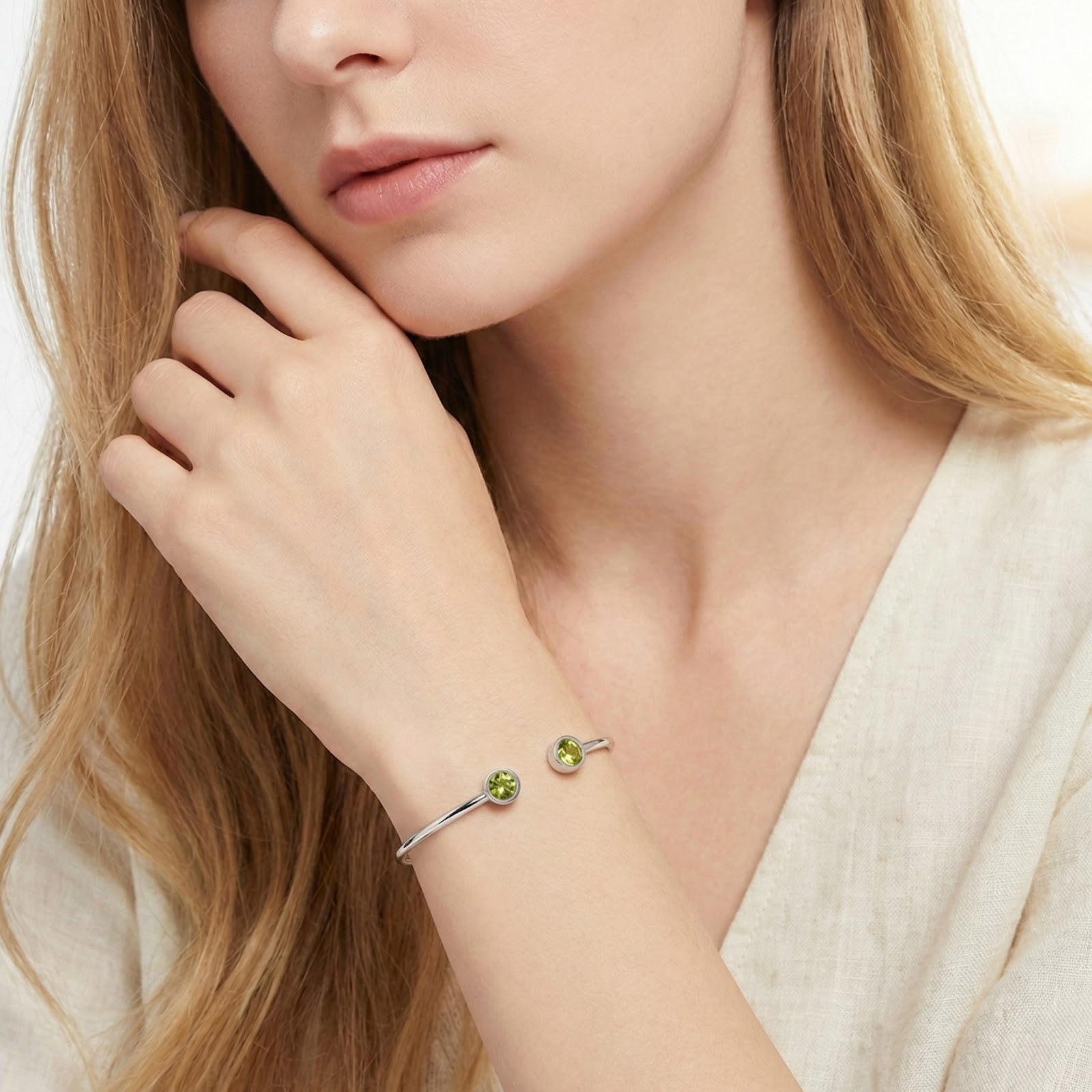Silver stainless steel Peridara cuff bracelet with round simulated peridots worn on a woman's wrist.