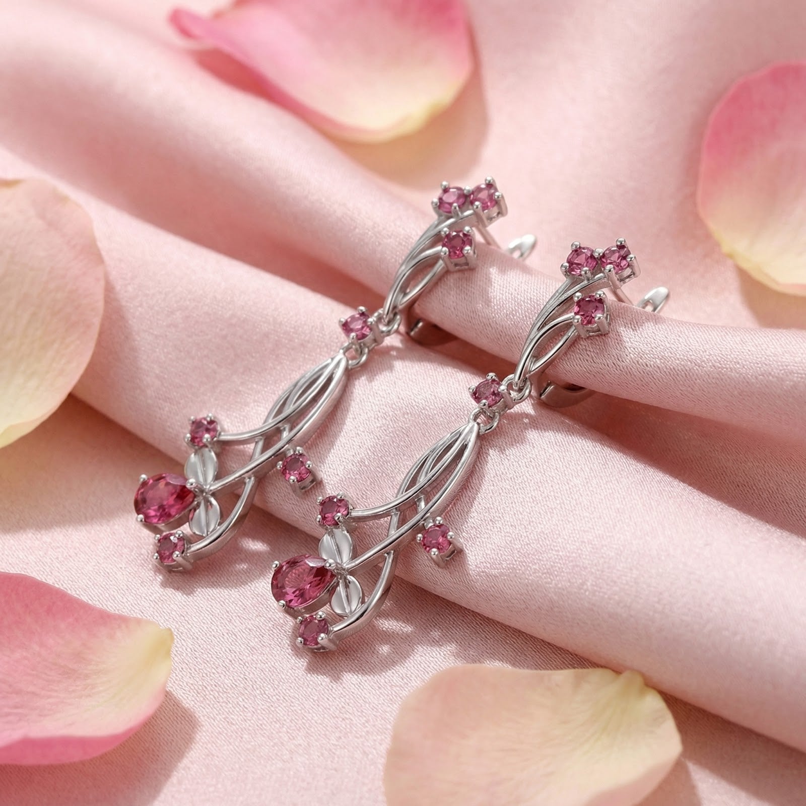 Angled view of sterling silver vine drop earrings featuring round and pear-cut simulated pink tourmaline.